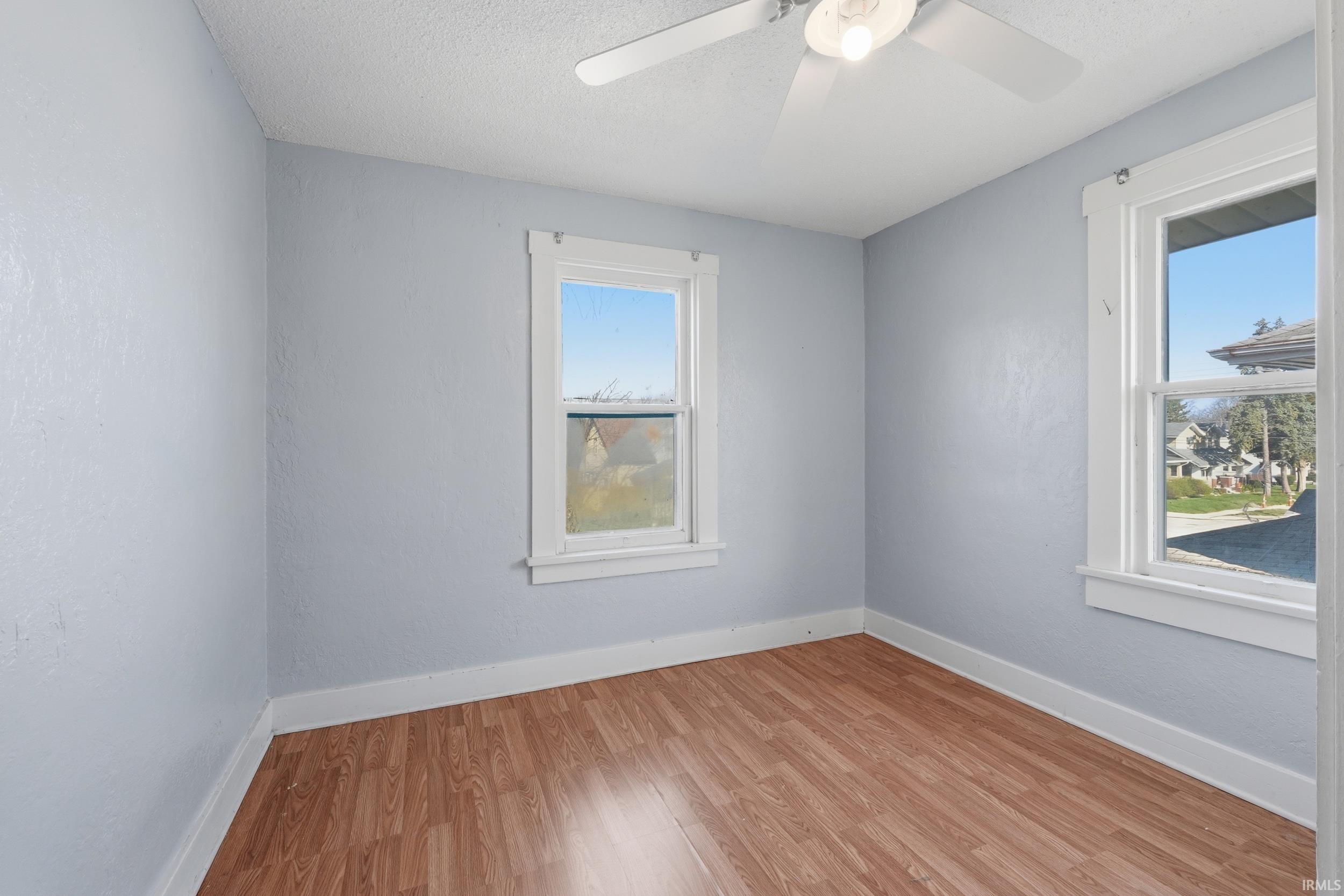 Unfurnished room with light wood-style flooring, a textured ceiling, and a ceiling fan