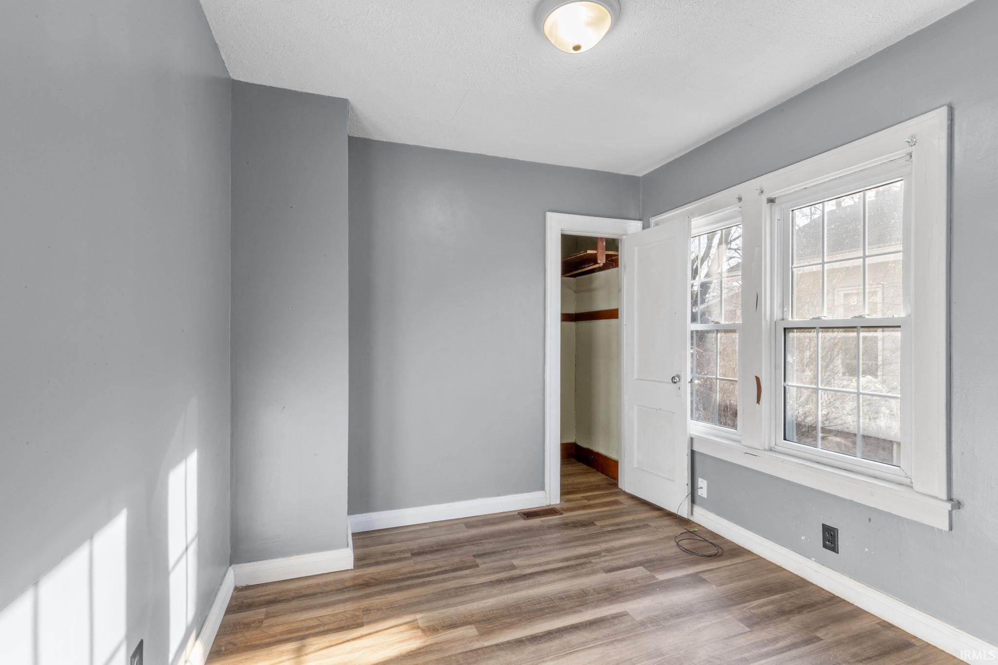 Unfurnished bedroom with light wood finished floors and a walk in closet
