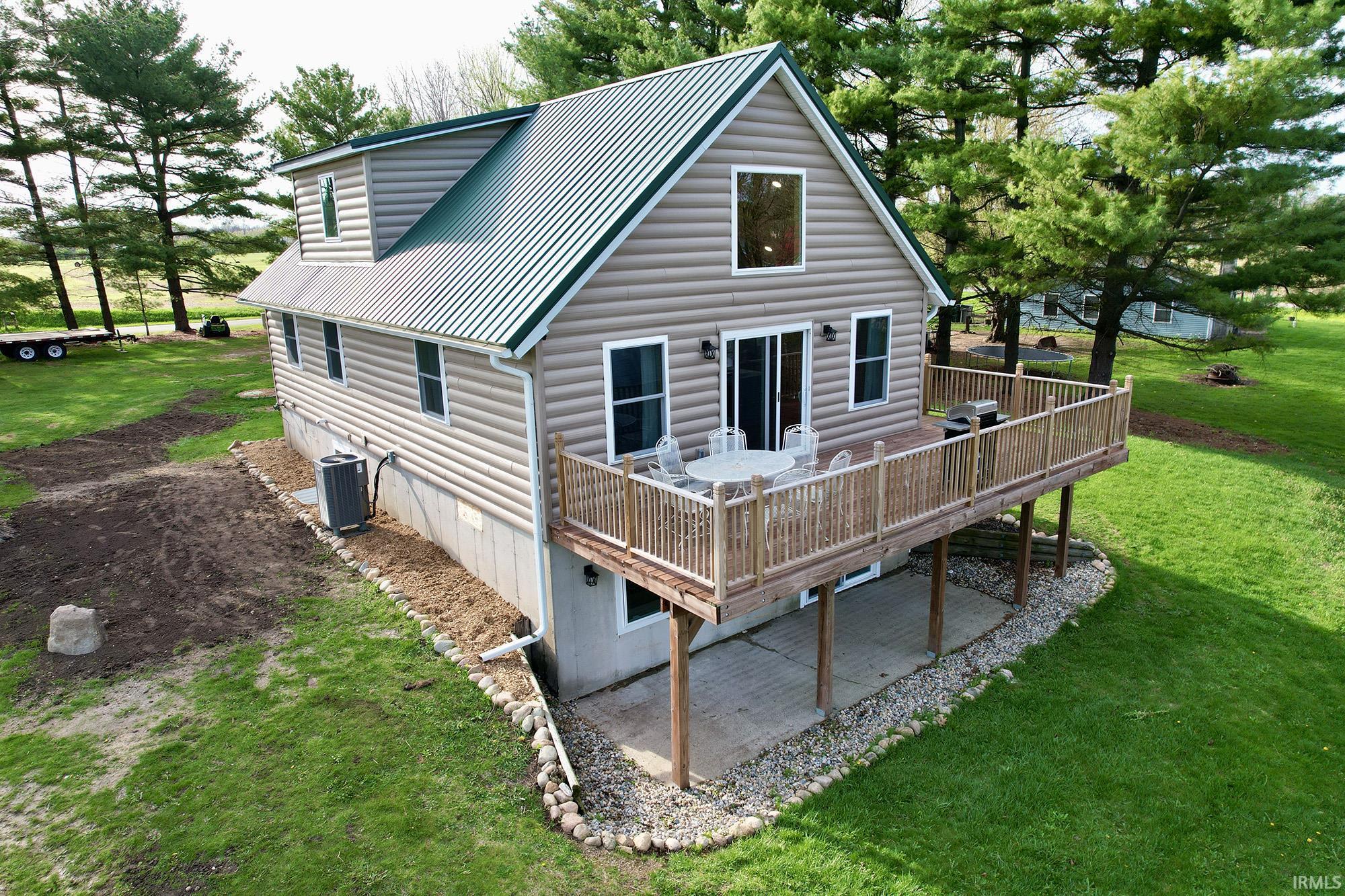 Rear view of property with a wooden deck, a yard, a metal roof, and a patio area
