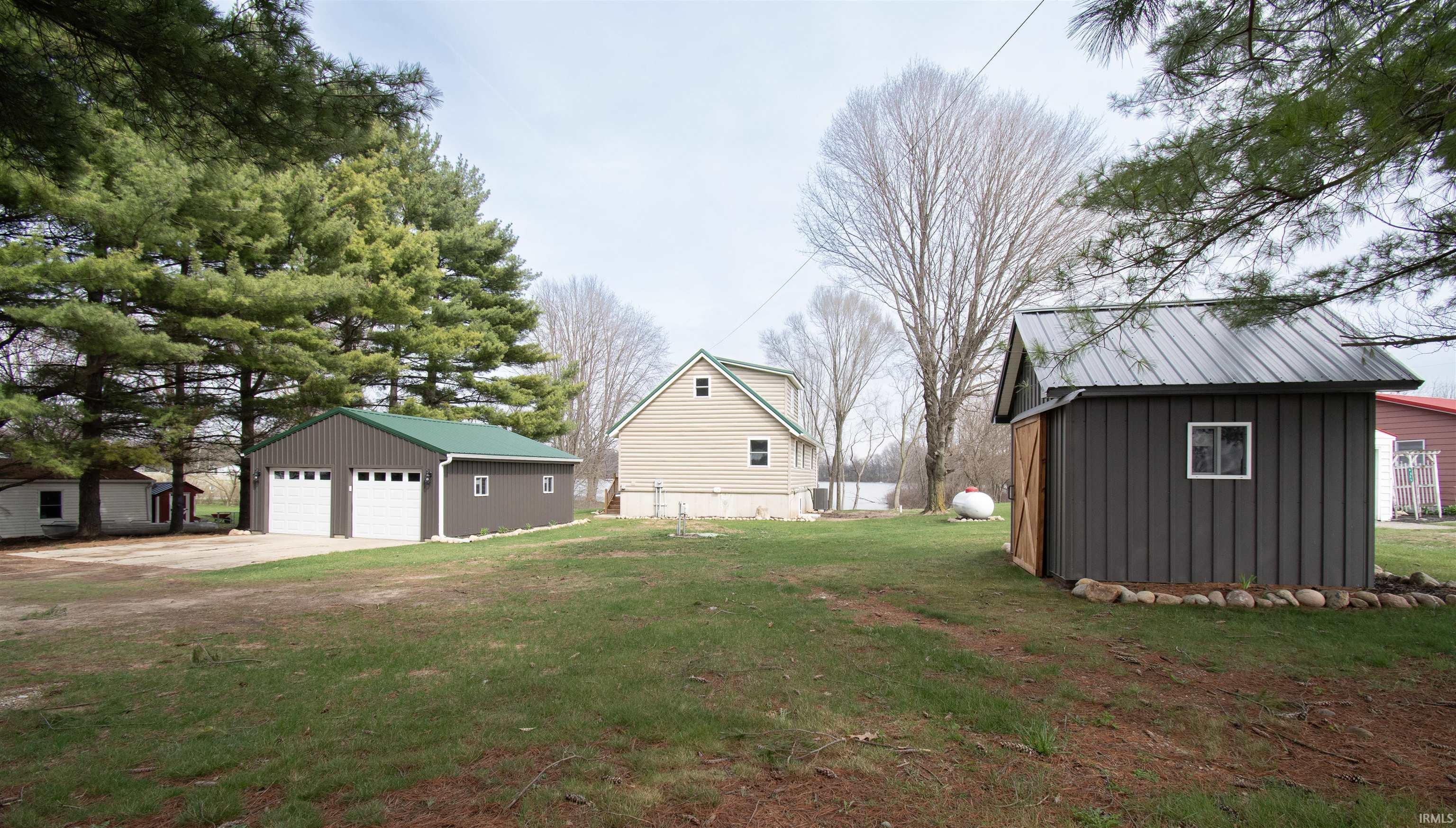 View of side of home featuring an outbuilding, a garage, a lawn, board and batten siding, and a metal roof