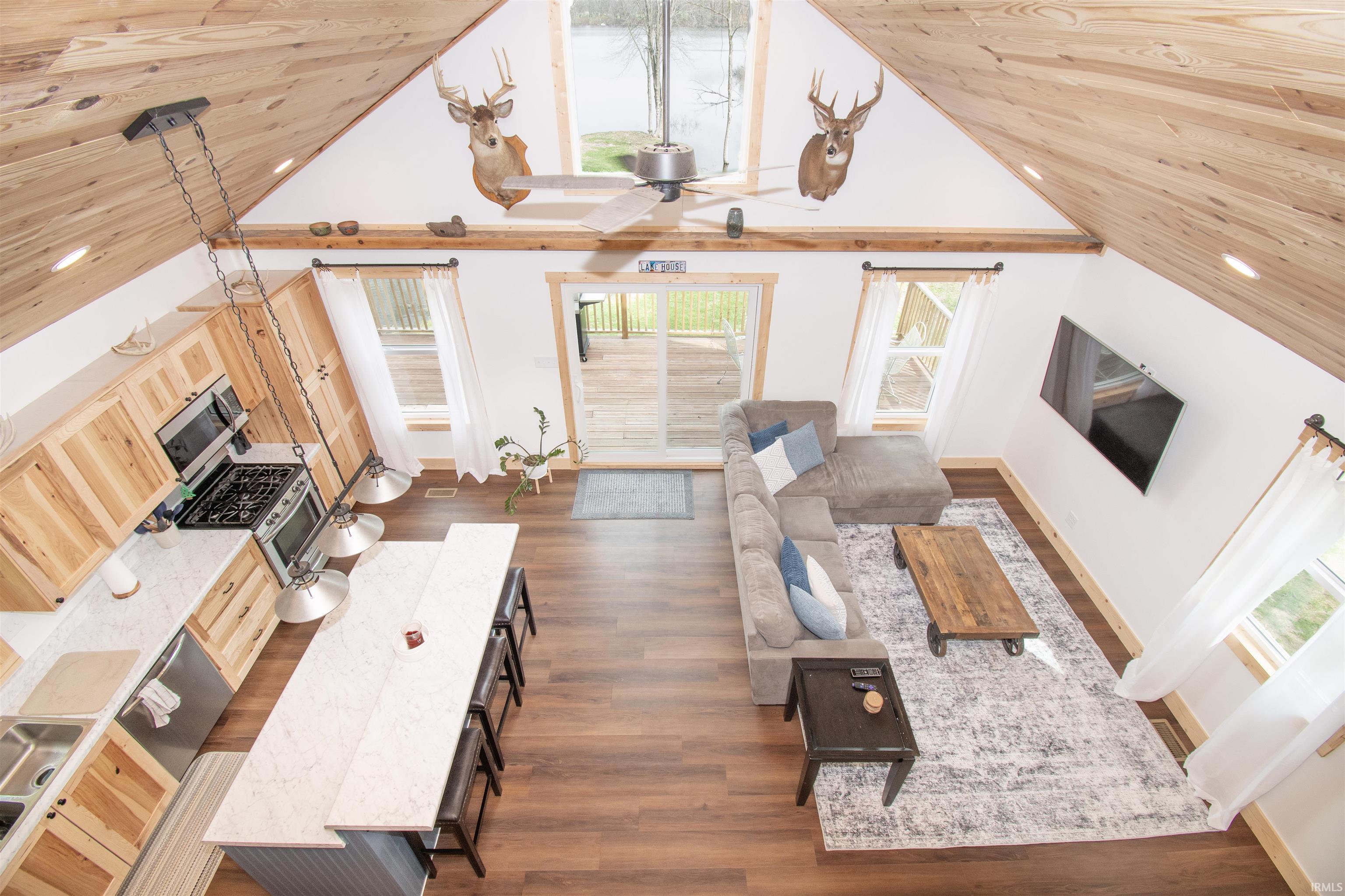 Living room featuring a high wooden ceiling, ceiling fan, and dark wood-style floors