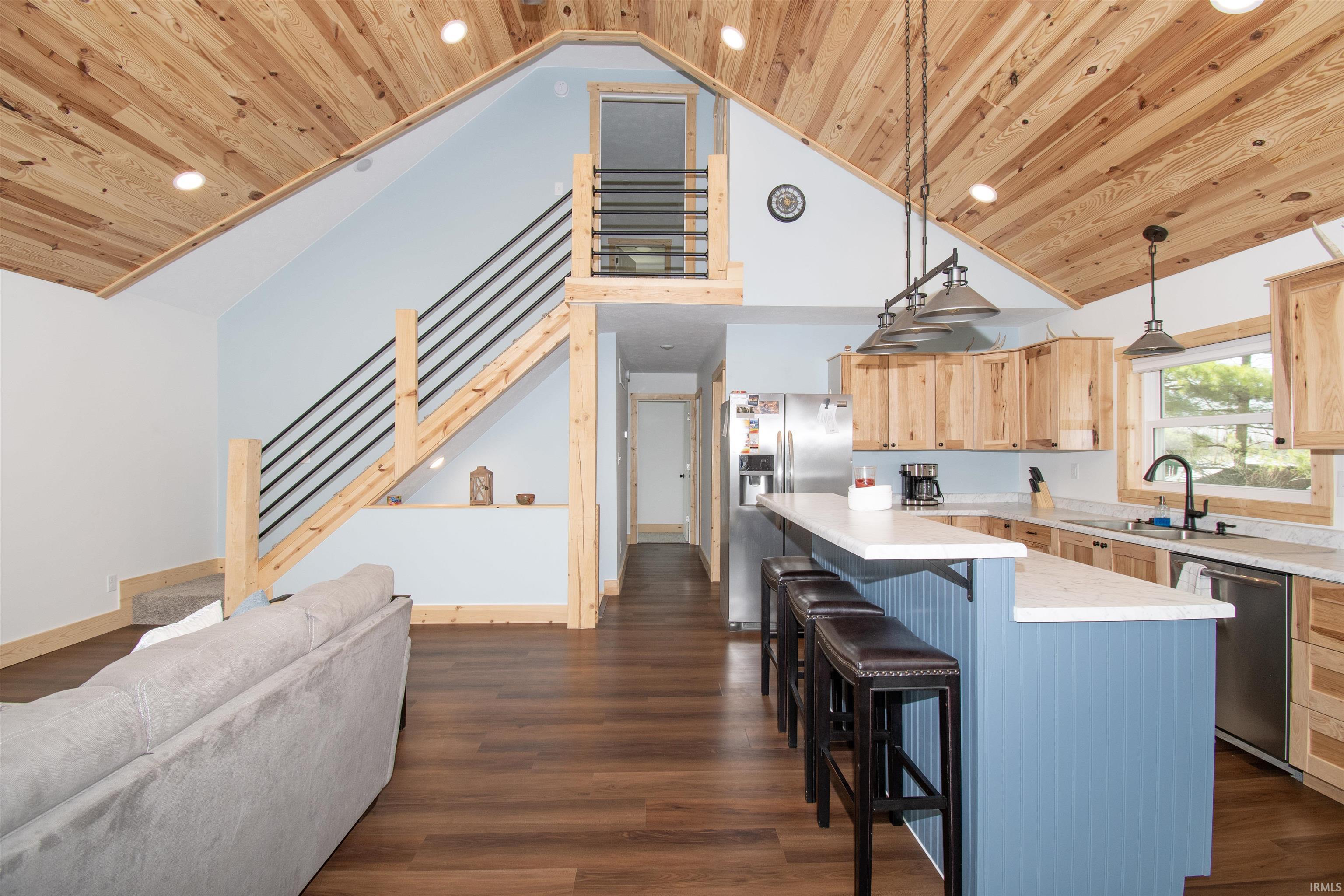 Kitchen featuring a high wood ceiling, stainless steel appliances, dark wood-type flooring, light countertops, and a center island