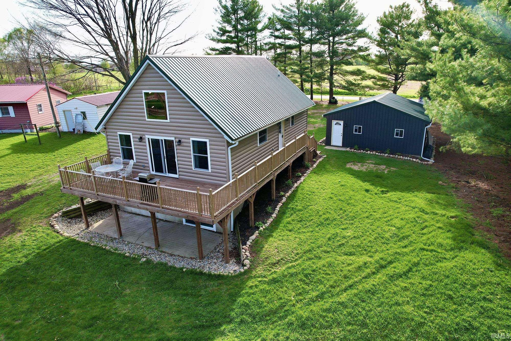 Back of property featuring a wooden deck, a yard, and a metal roof