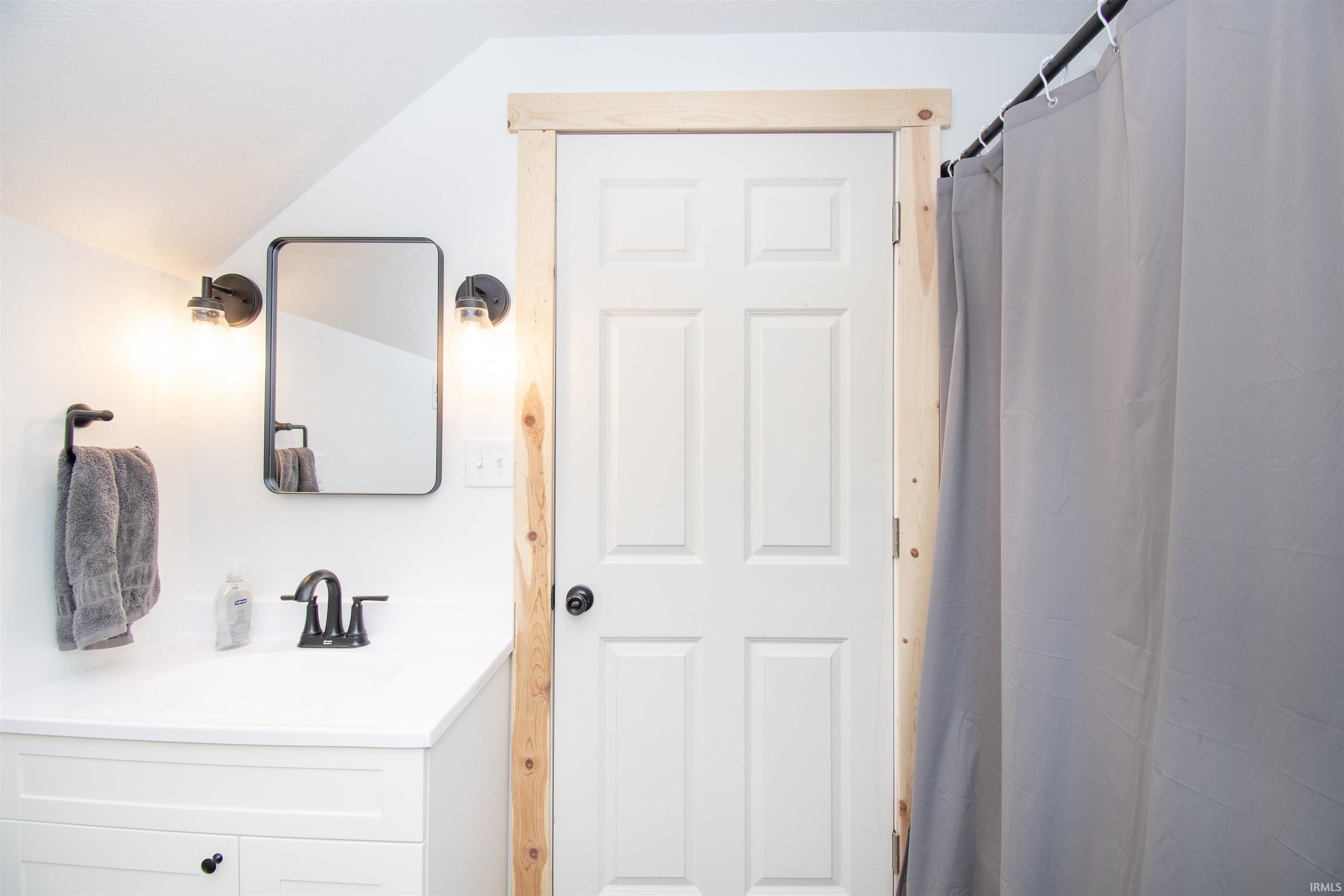 Bathroom with a shower with curtain and vanity