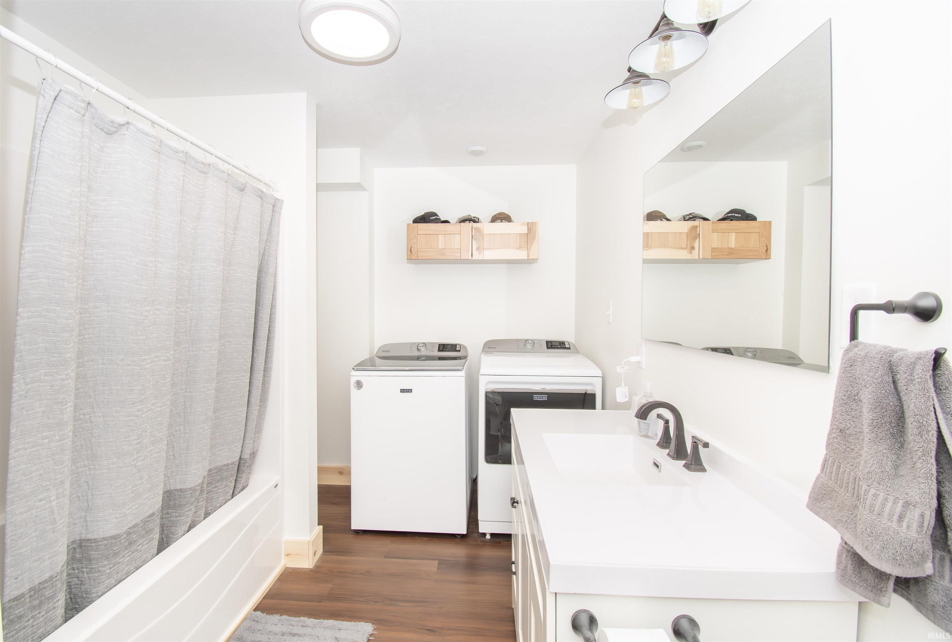 Full bath with vanity, dark wood-style floors, independent washer and dryer, and shower / bath combination with curtain