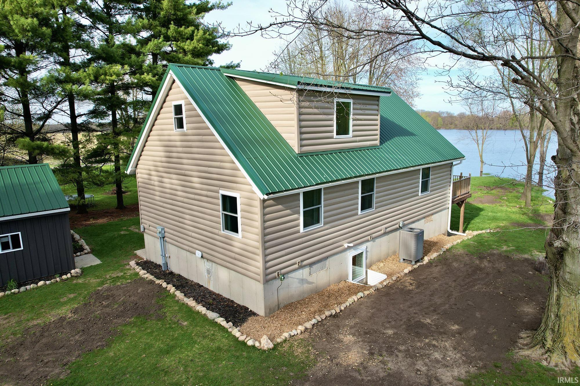 View of side of home featuring a metal roof, a lawn, and a water view