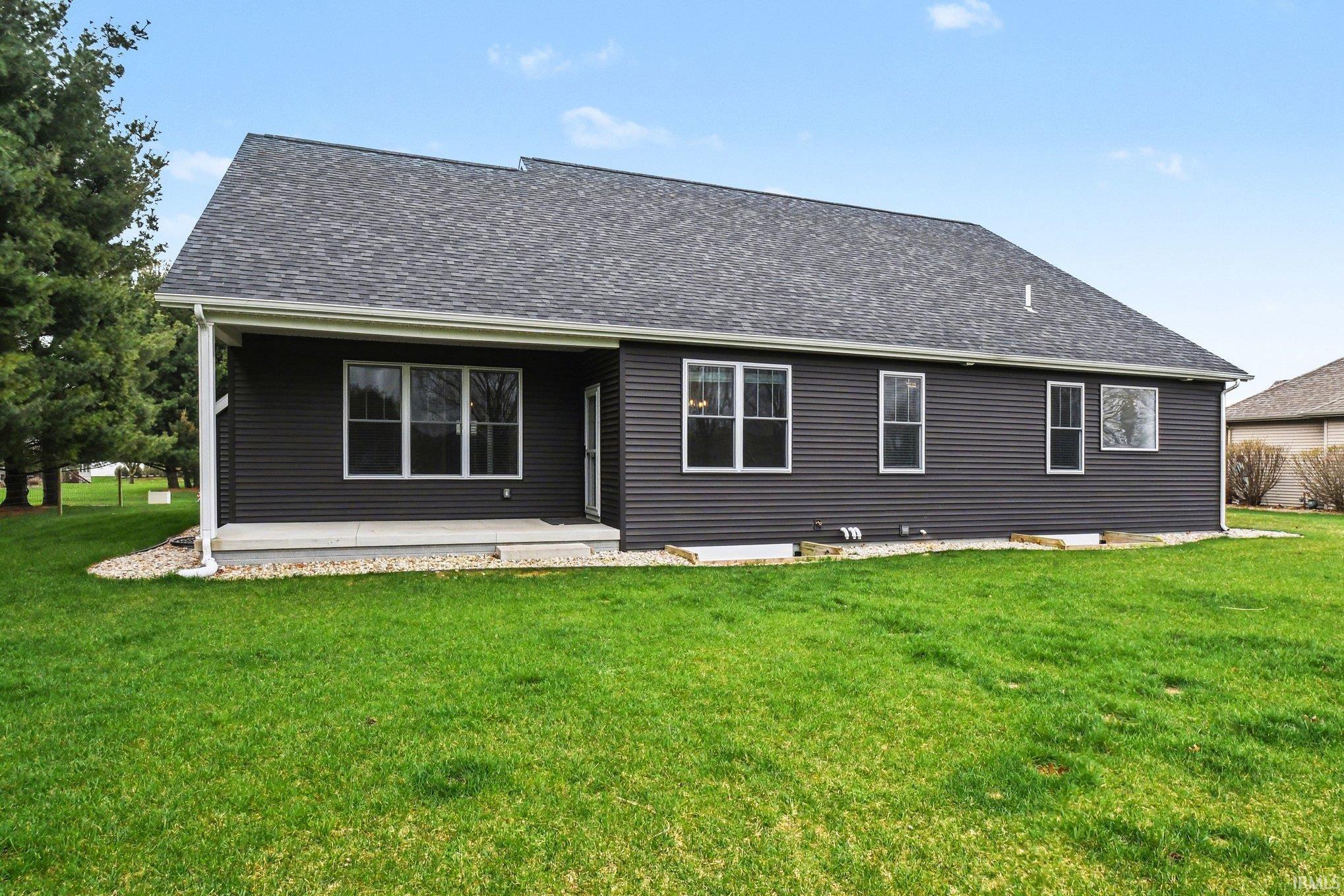 Back of property featuring a yard, a shingled roof, and a patio area