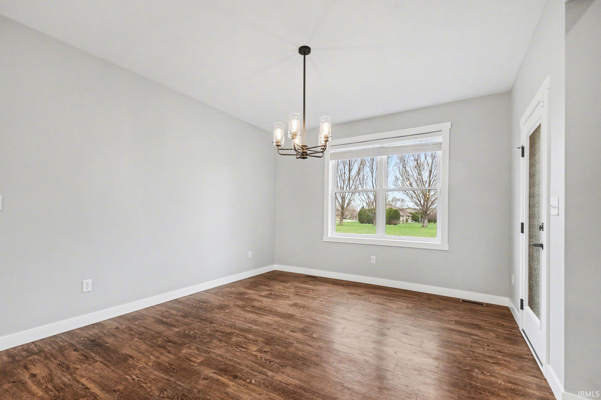 Spare room with dark wood-style floors and suspended lighting