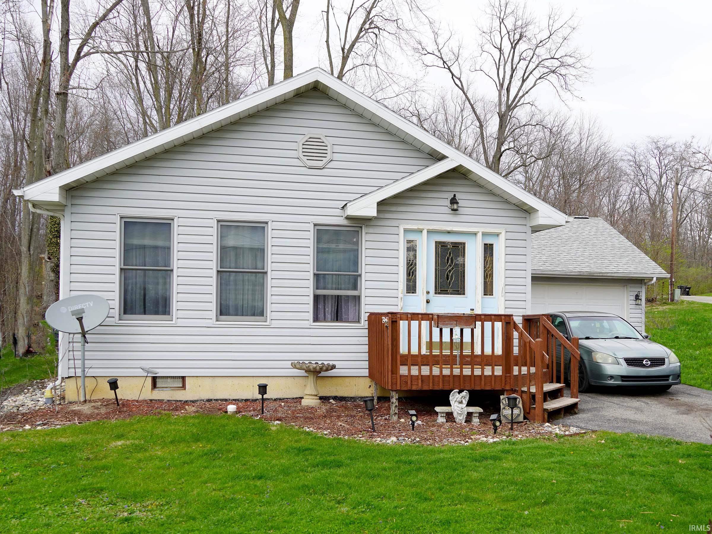 Single story home featuring a wooden deck, a front yard, driveway, crawl space, and roof with shingles