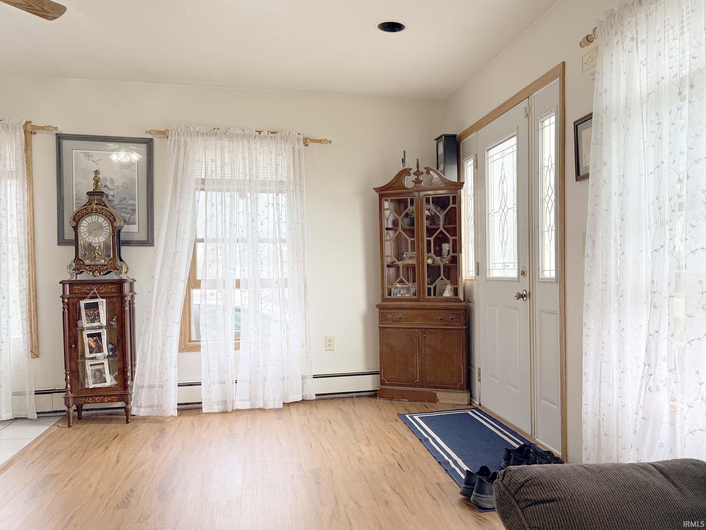 Foyer entrance featuring plenty of natural light, light wood finished floors, and a baseboard radiator
