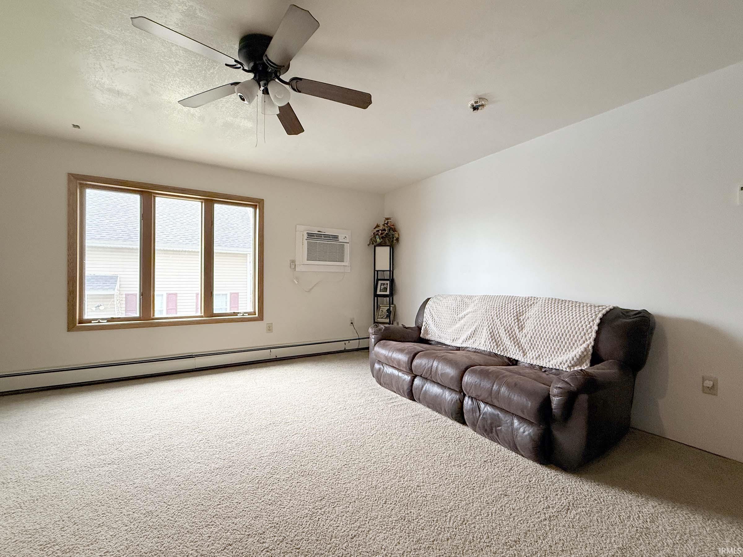 Sitting room with a baseboard radiator, carpet, and a ceiling fan