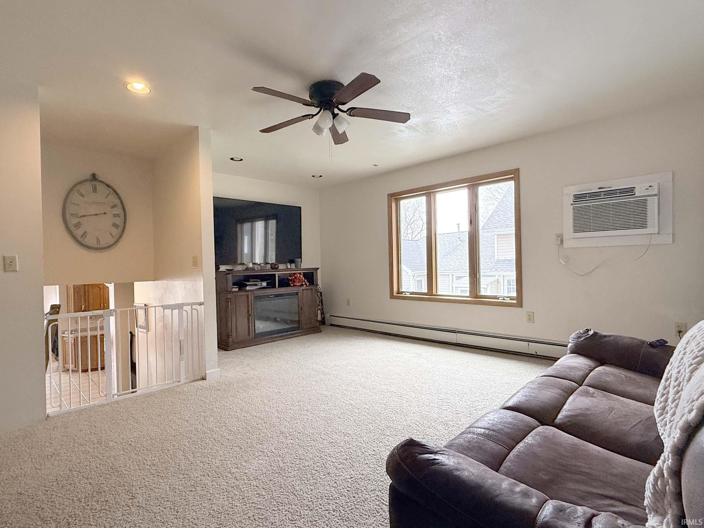 Living area with a ceiling fan, baseboard heating, light carpet, recessed lighting, and a fireplace