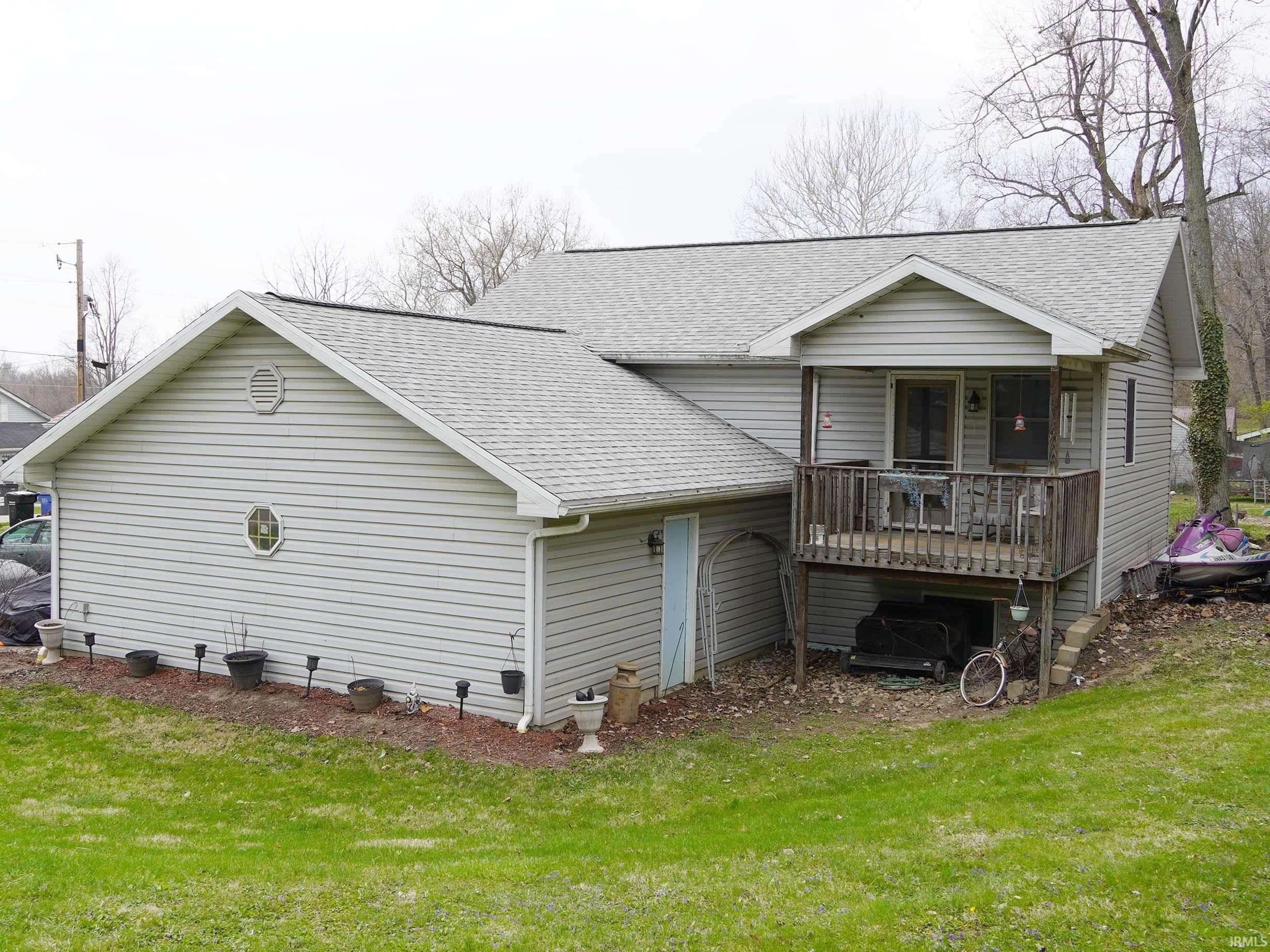 View of side of home with a shingled roof and a yard