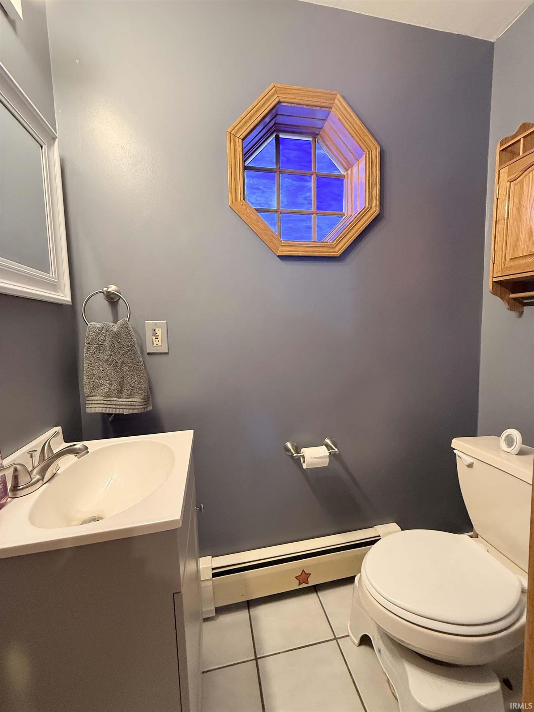 Bathroom with a baseboard heating unit, vanity, and light tile patterned flooring