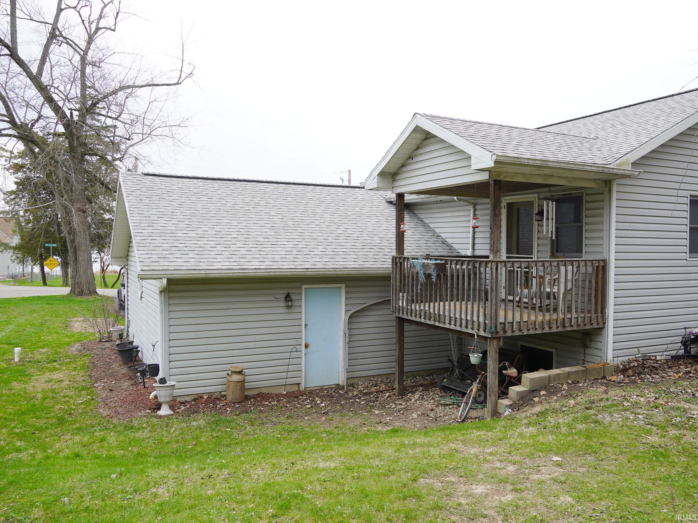 Back of house featuring a shingled roof, a yard, and a wooden deck