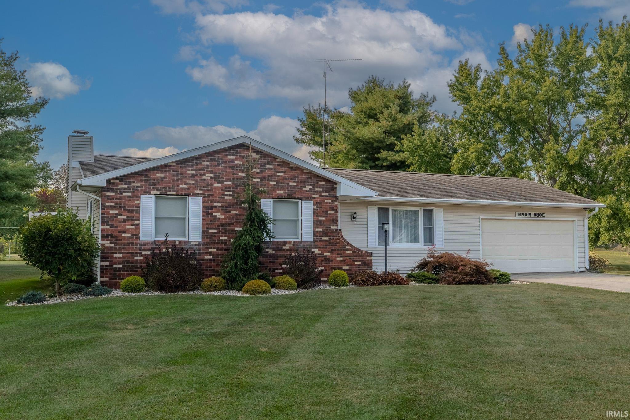 Ranch-style house with a chimney, an attached garage, a front yard, and concrete driveway