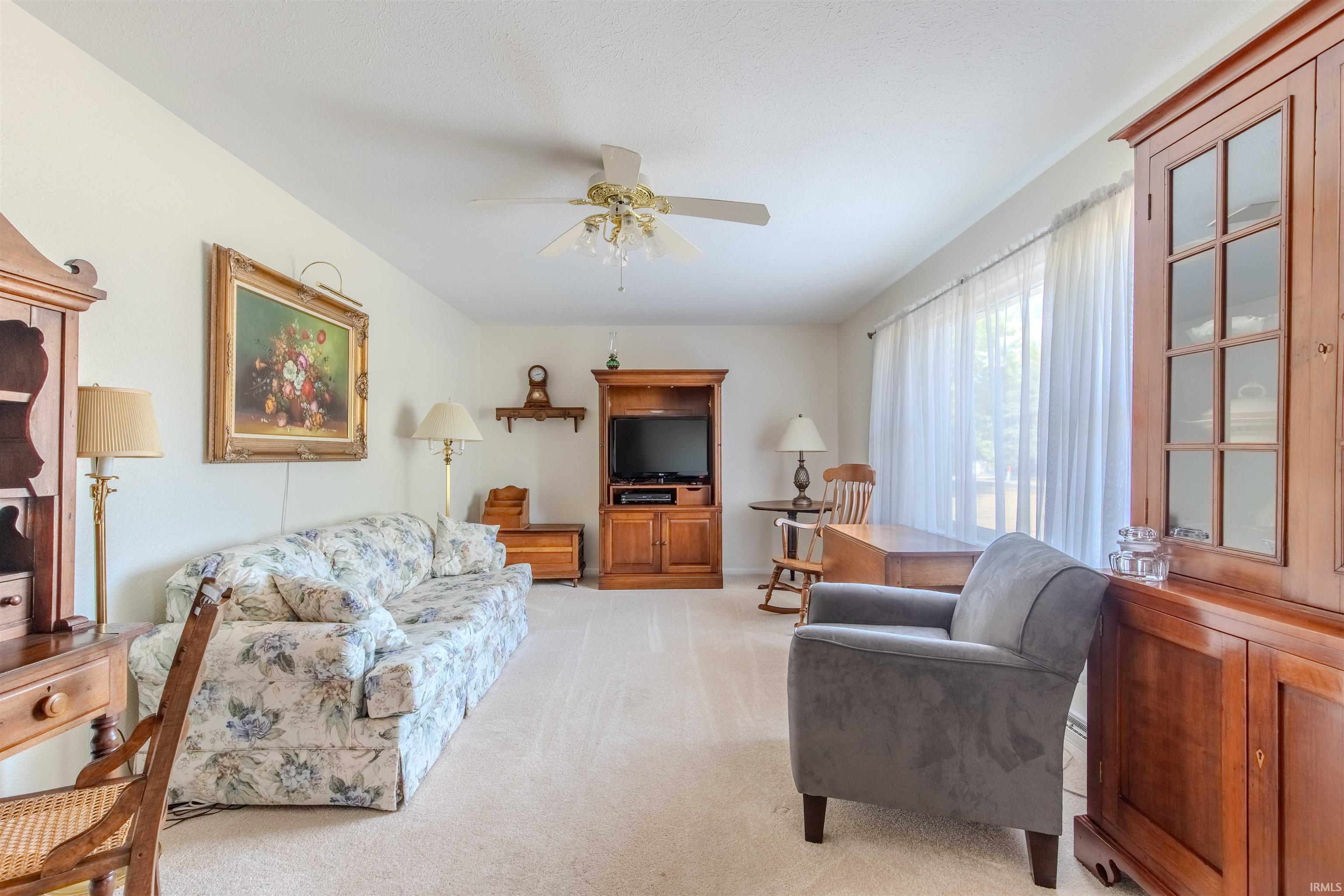 Living area featuring light colored carpet and a ceiling fan
