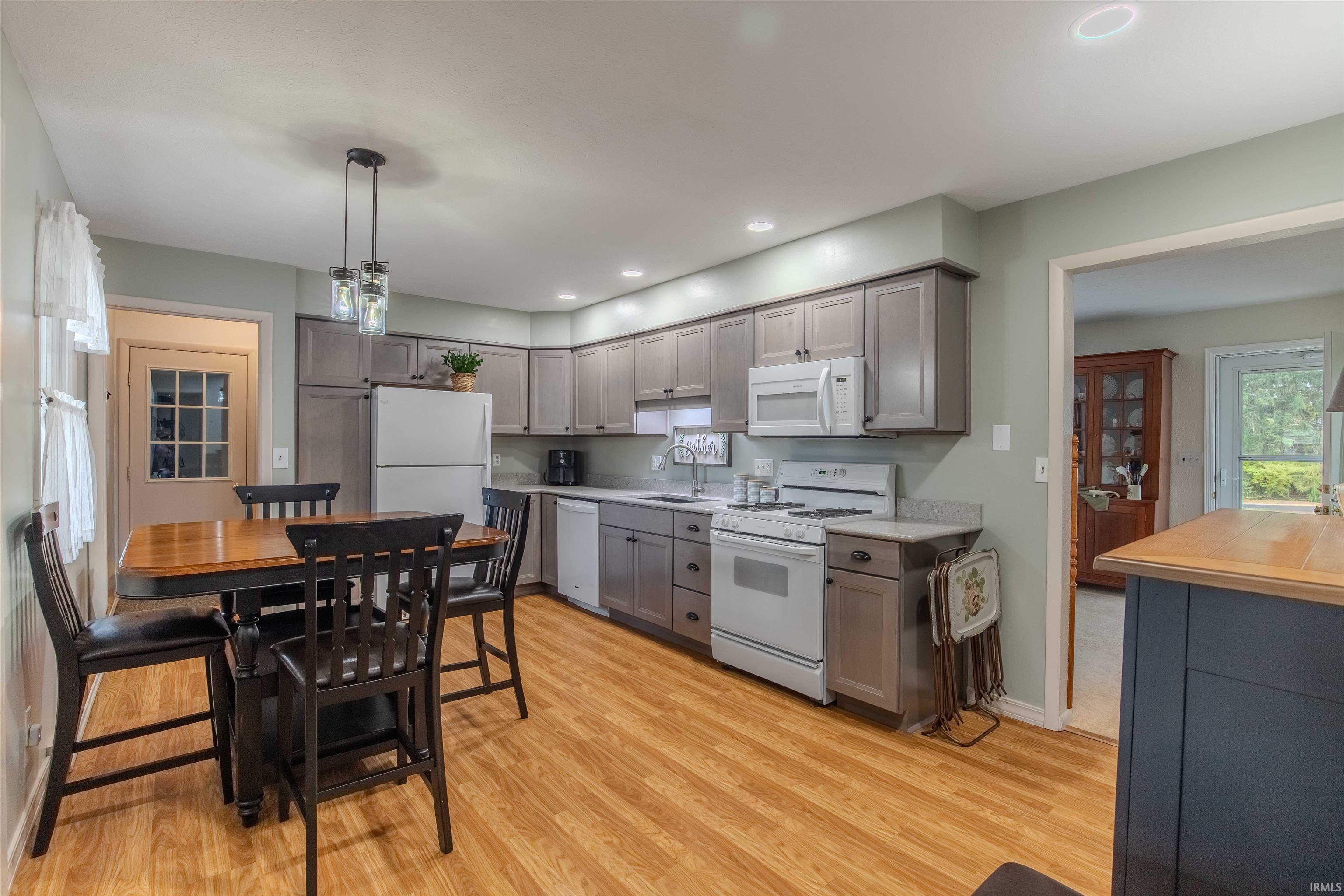 Kitchen with white appliances, gray cabinetry, and light wood-type flooring
