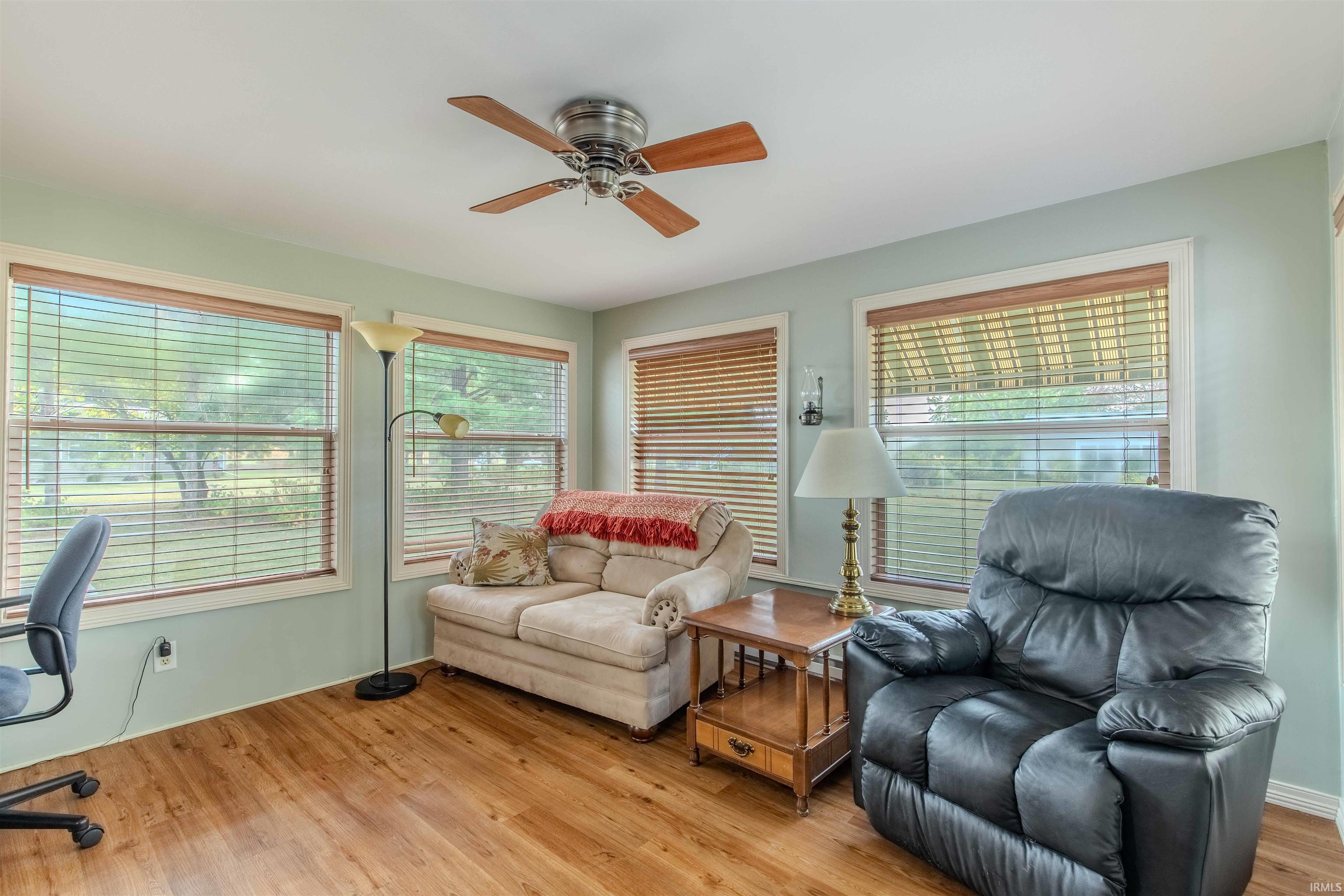 Living room featuring light wood finished floors, ceiling fan, and an office area