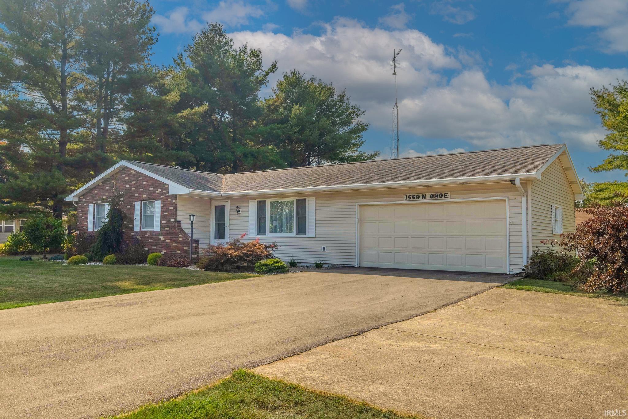 Ranch-style house featuring asphalt driveway, a garage, and a front yard