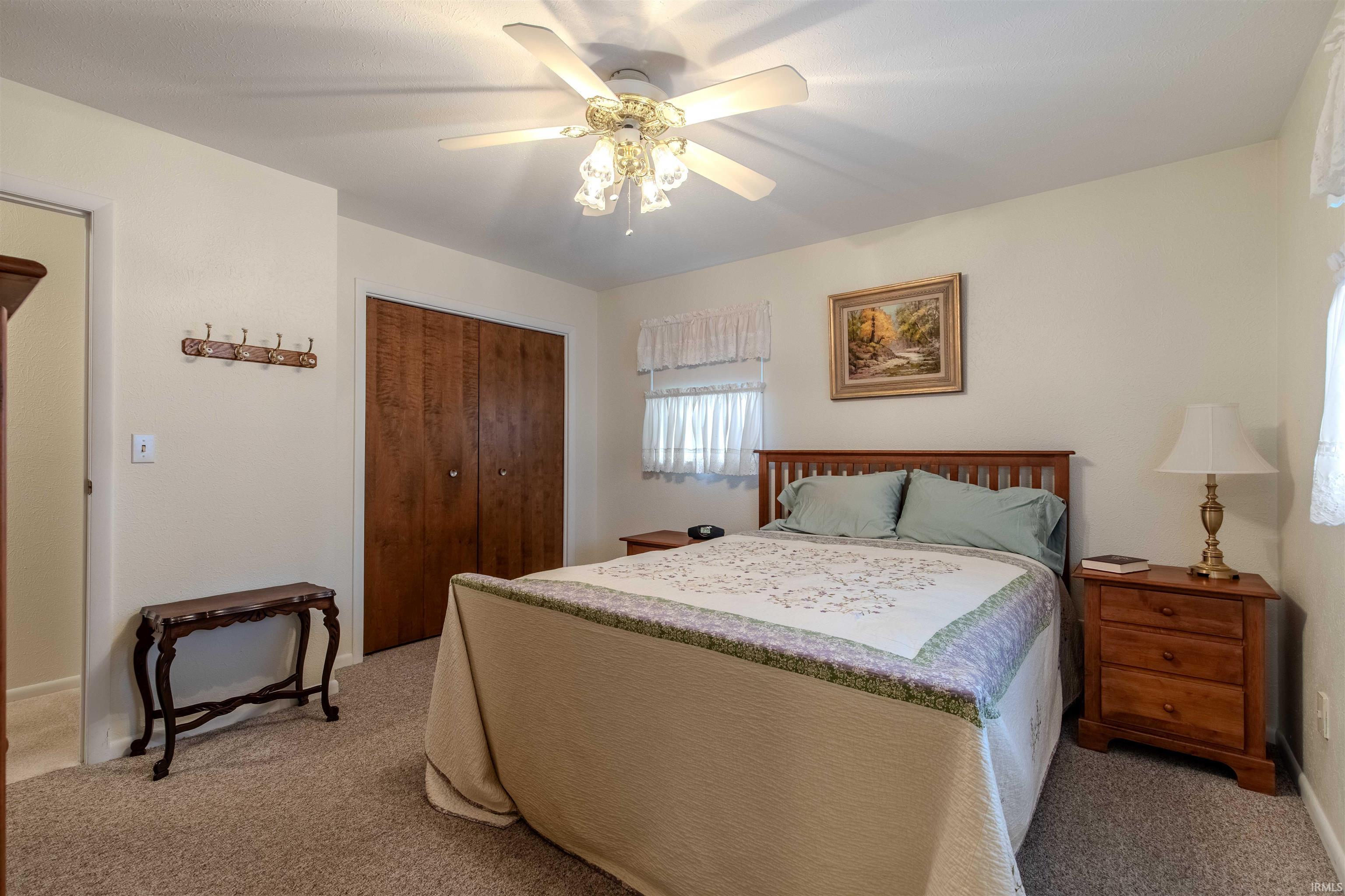Bedroom featuring a closet, light colored carpet, and ceiling fan