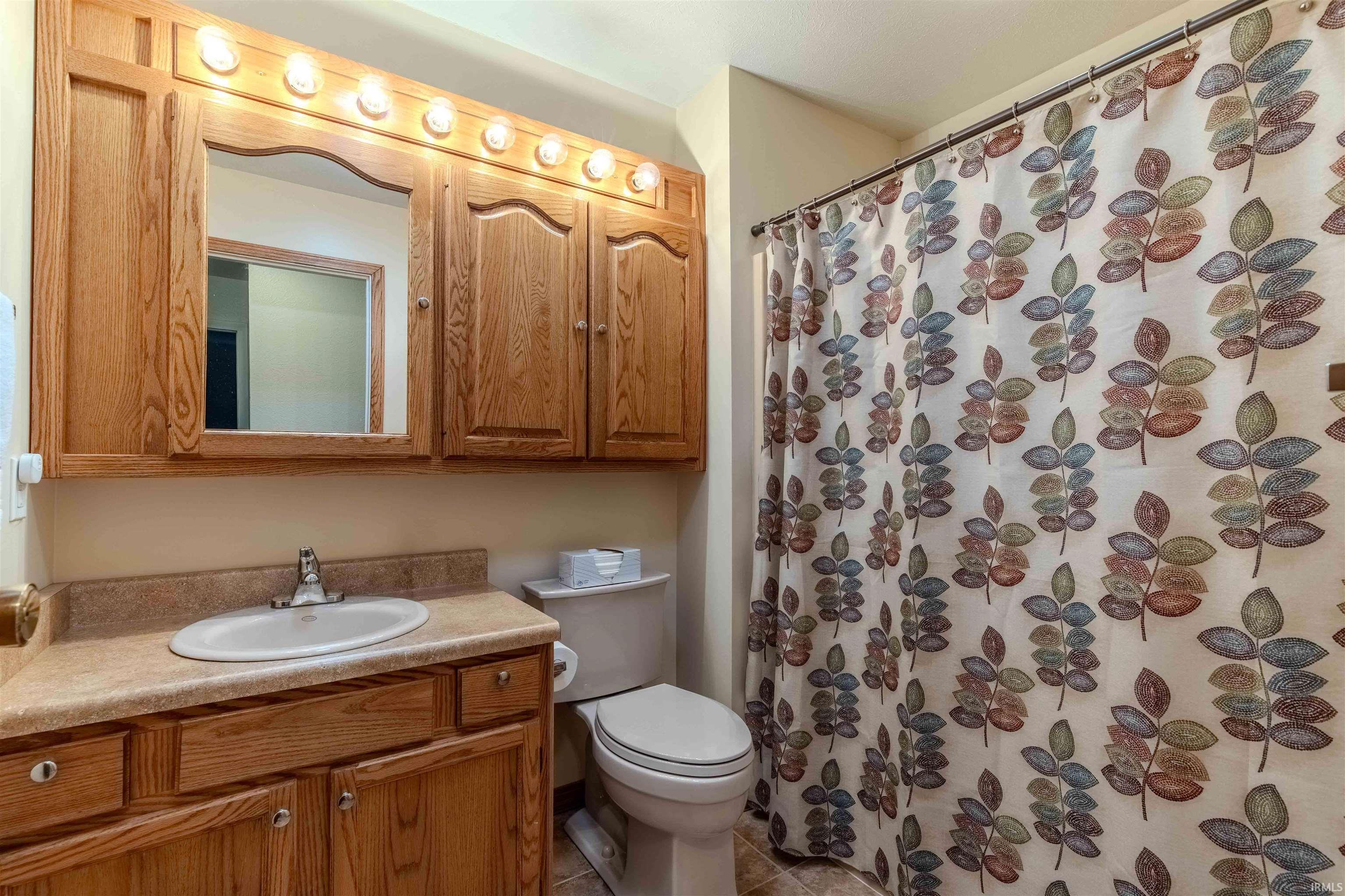 Full bath featuring vanity, a shower with curtain, and light tile patterned floors