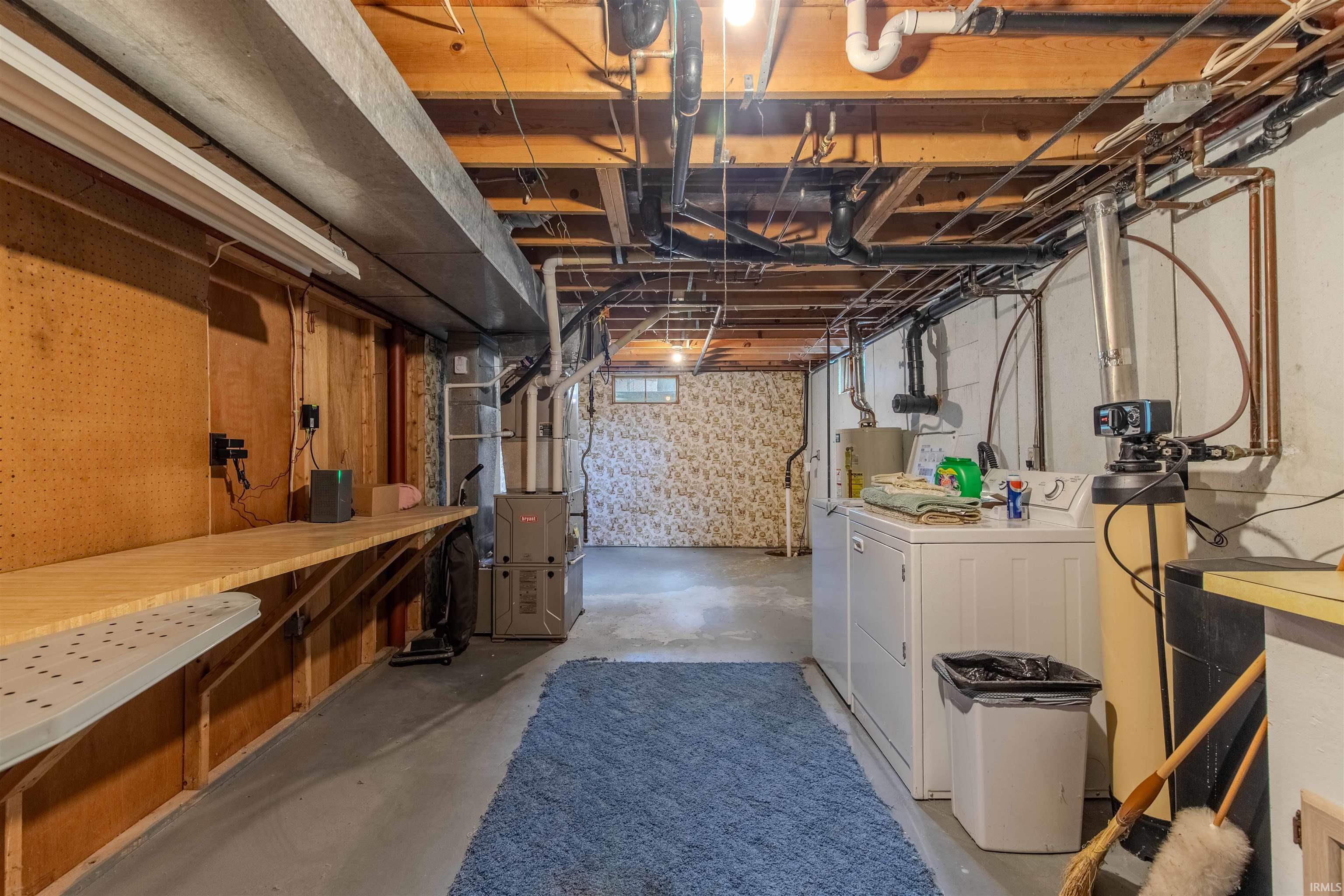 Unfinished basement featuring heating unit, independent washer and dryer, and water heater