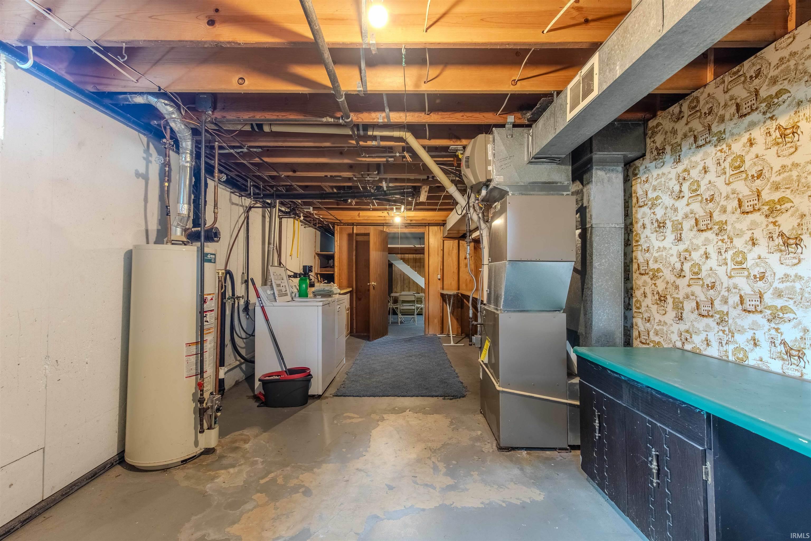 Unfinished basement featuring gas water heater, separate washer and dryer, and heating unit