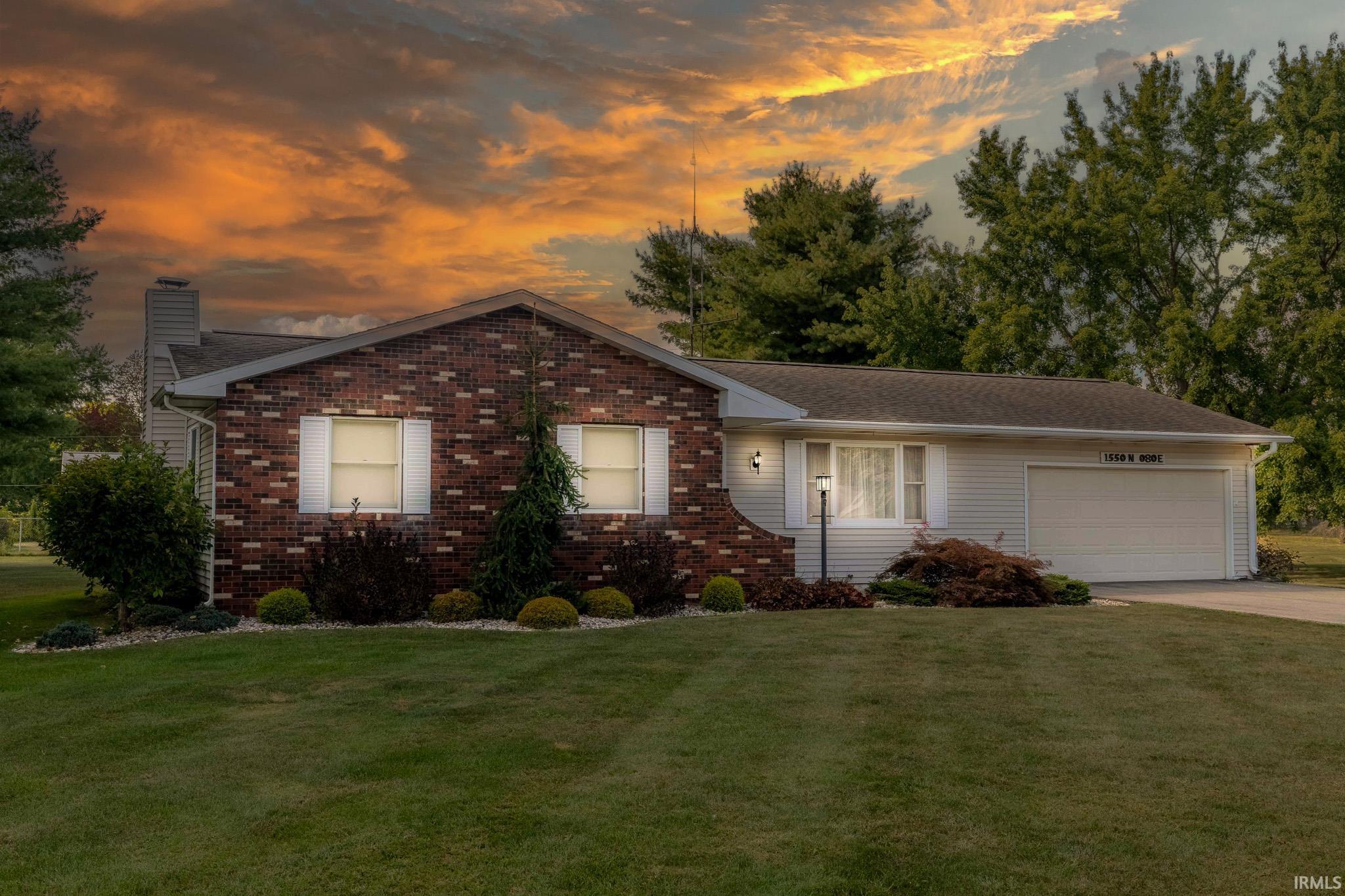 Single story home with a garage, a chimney, a lawn, and concrete driveway