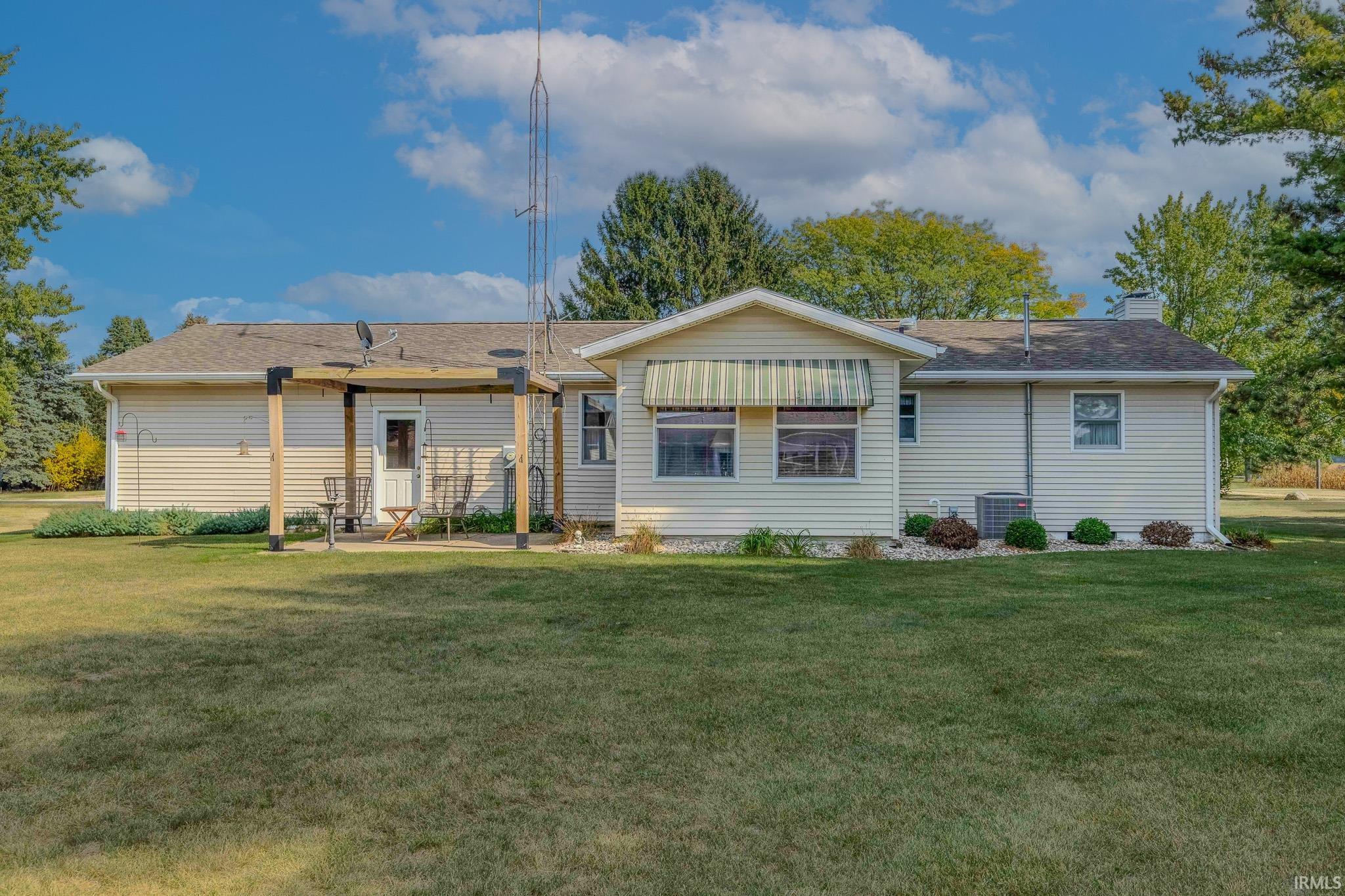 Back of property featuring a yard, a chimney, and roof with shingles
