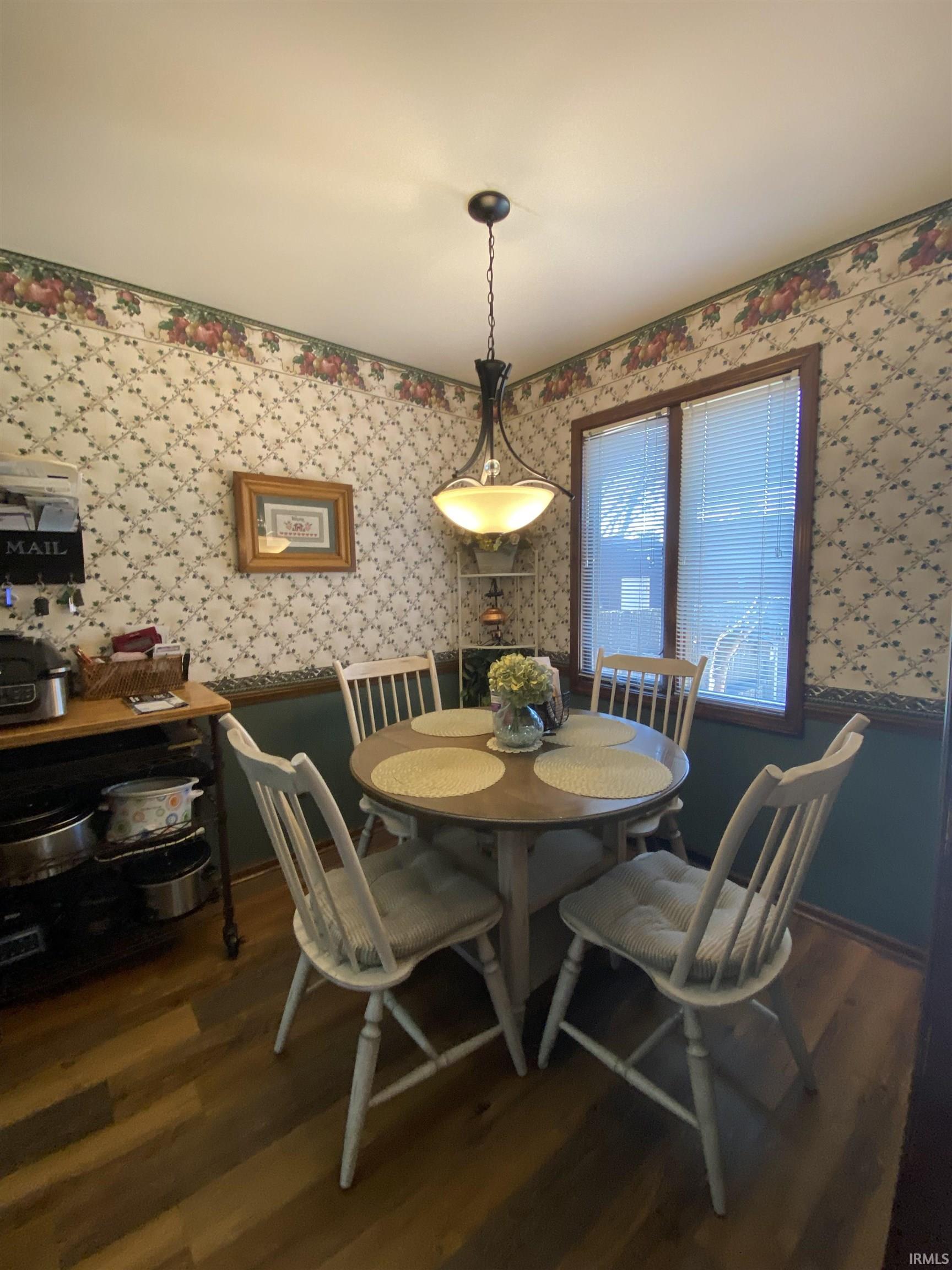 Dining area with dark wood-style flooring and wallpapered walls