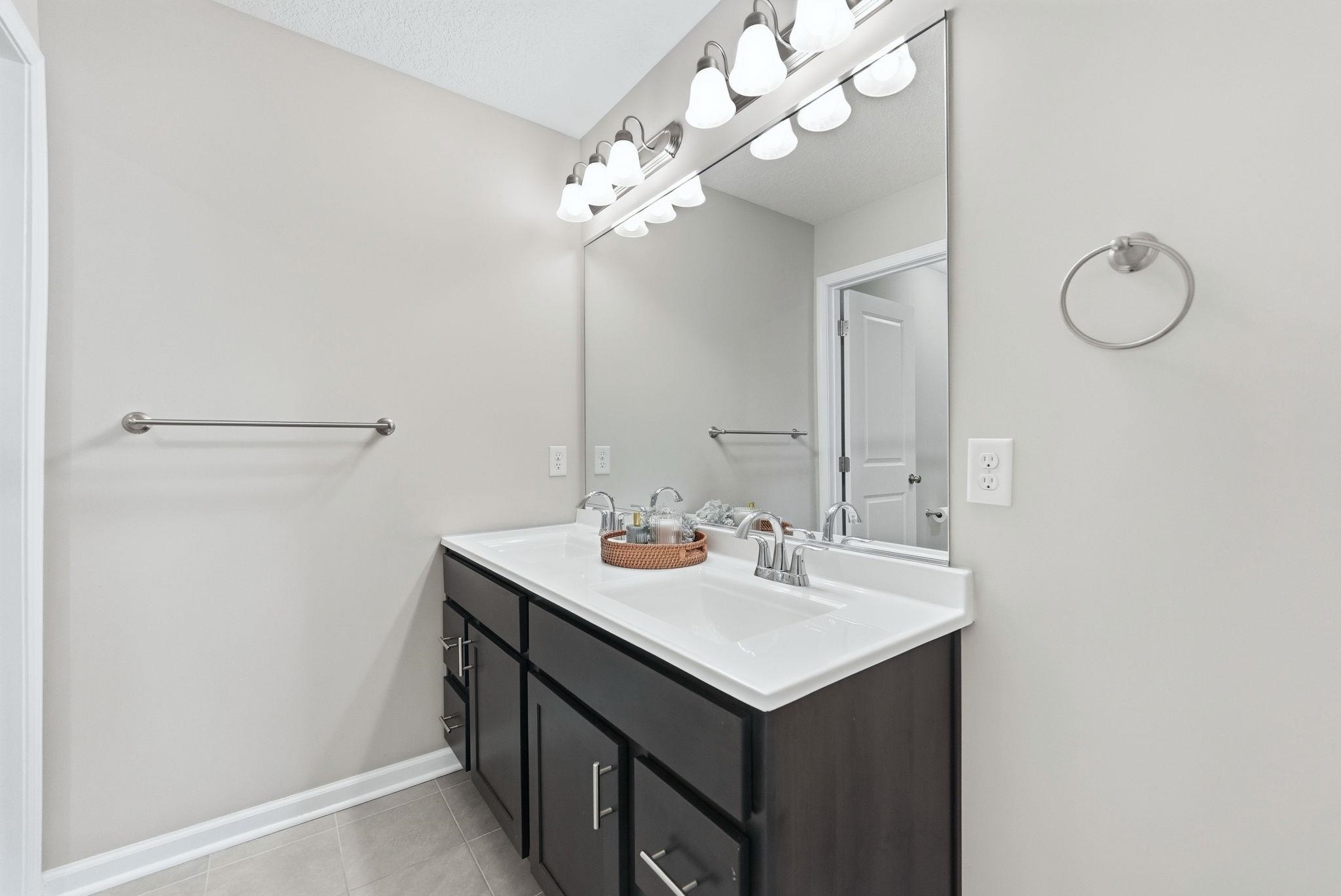 Full bathroom with double vanity and light tile patterned floors