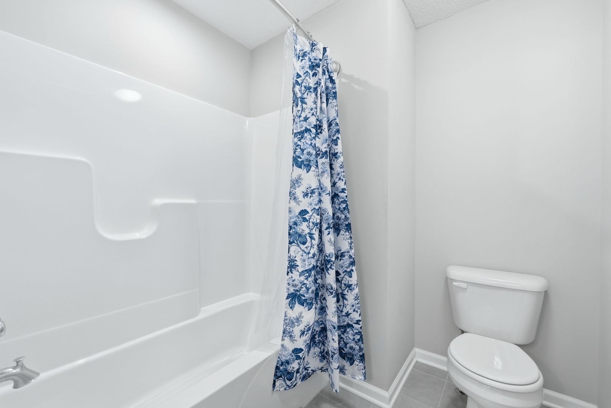 Bathroom with light tile patterned flooring and shower / bath combo