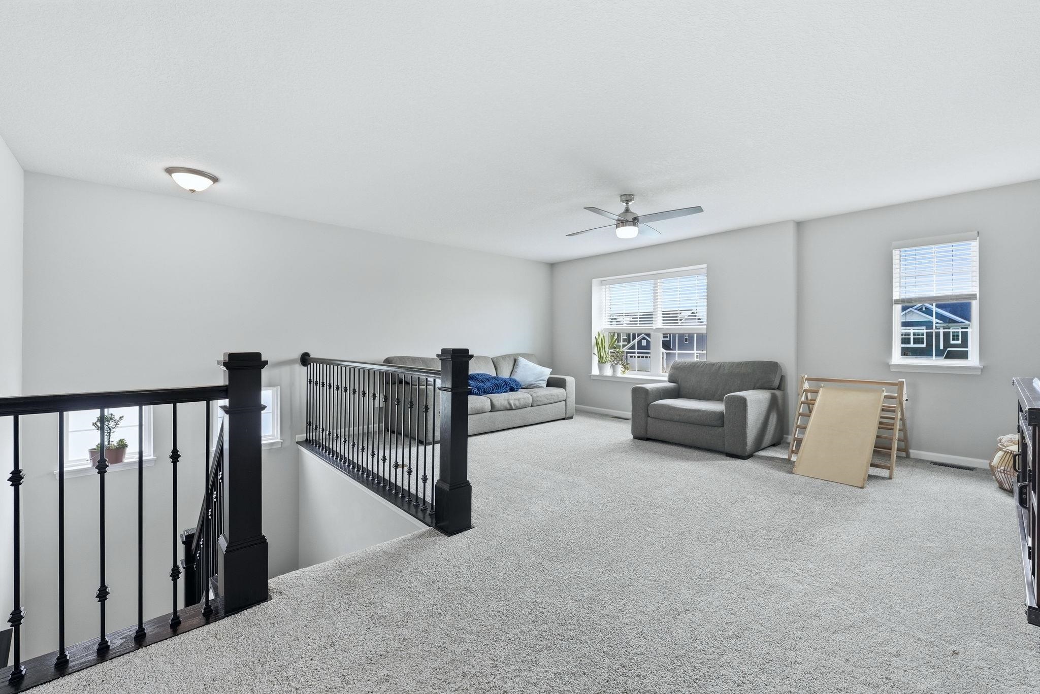 Carpeted living room with a ceiling fan and baseboards