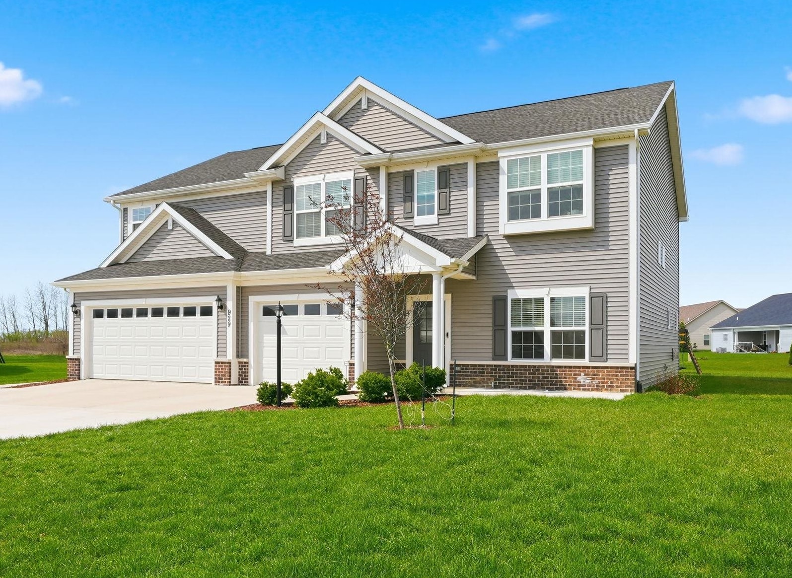 View of front of house with a front lawn, concrete driveway, brick siding, and an attached garage