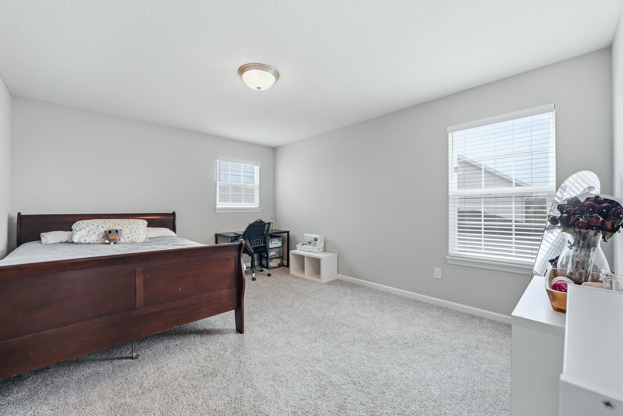 Bedroom featuring light carpet and a desk