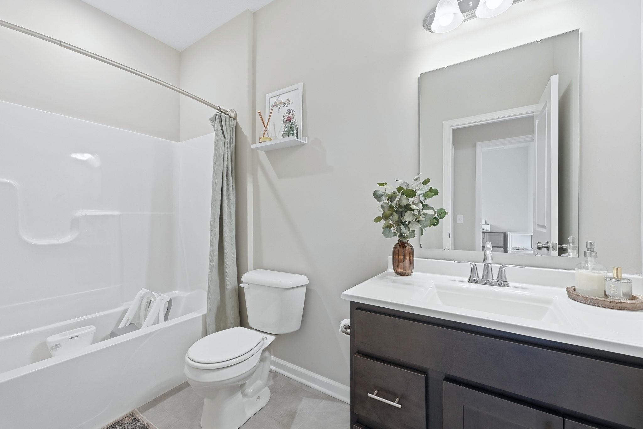 Full bathroom with vanity, shower / tub combo with curtain, and light tile patterned floors