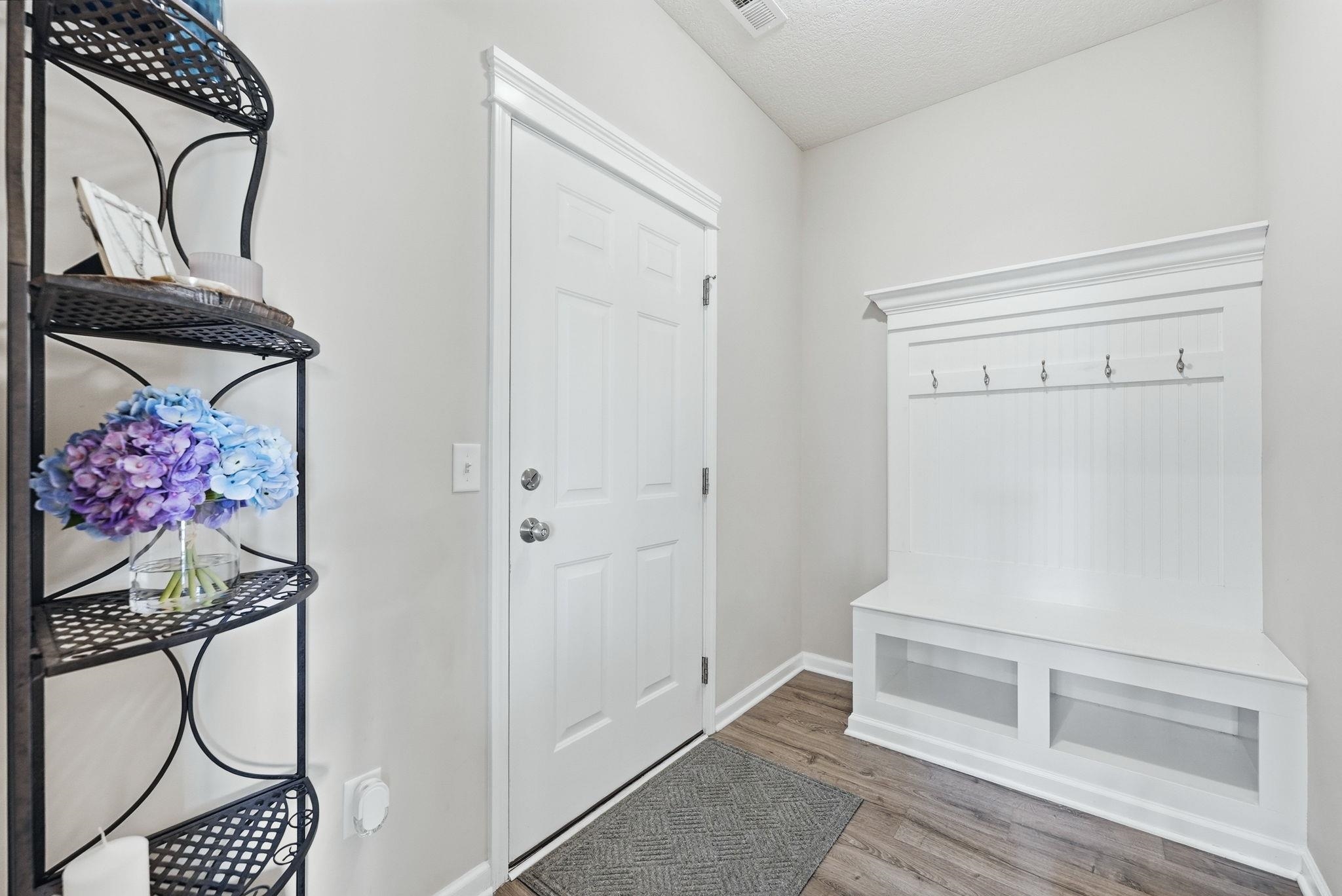 Mudroom featuring light wood finished floors and a textured ceiling
