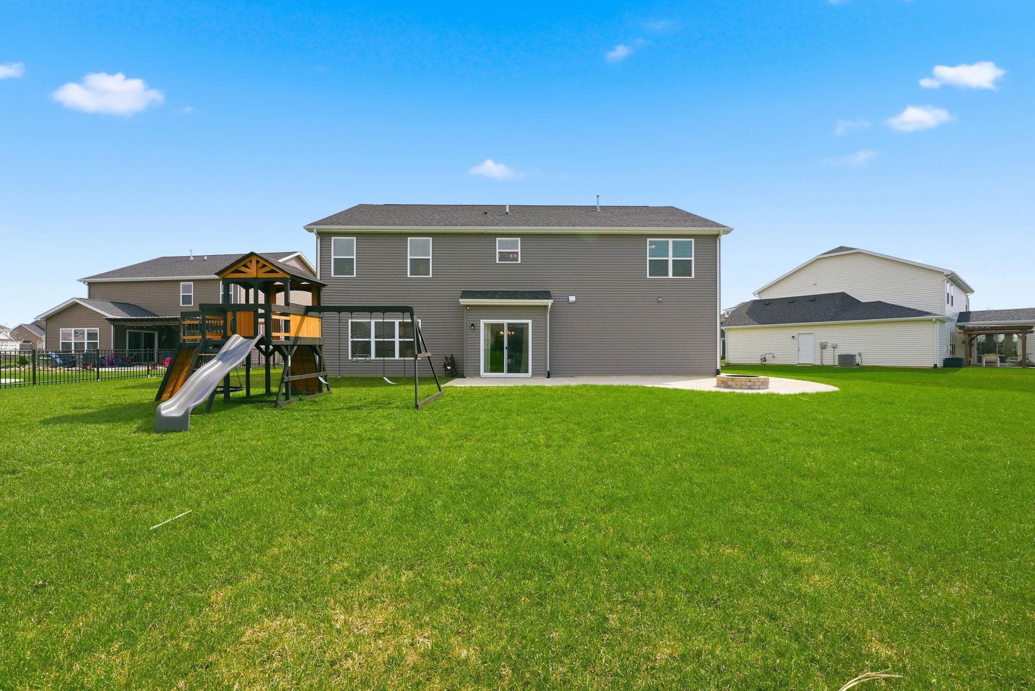 Rear view of house with a patio, a lawn, a playground, and an outdoor fire pit