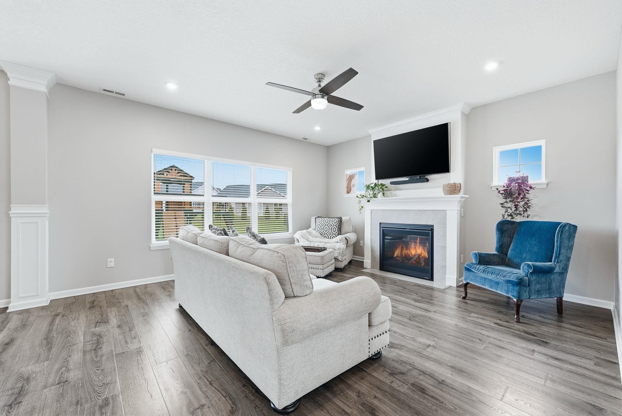 Living room featuring a fireplace, light wood-style floors, a ceiling fan, plenty of natural light, and recessed lighting