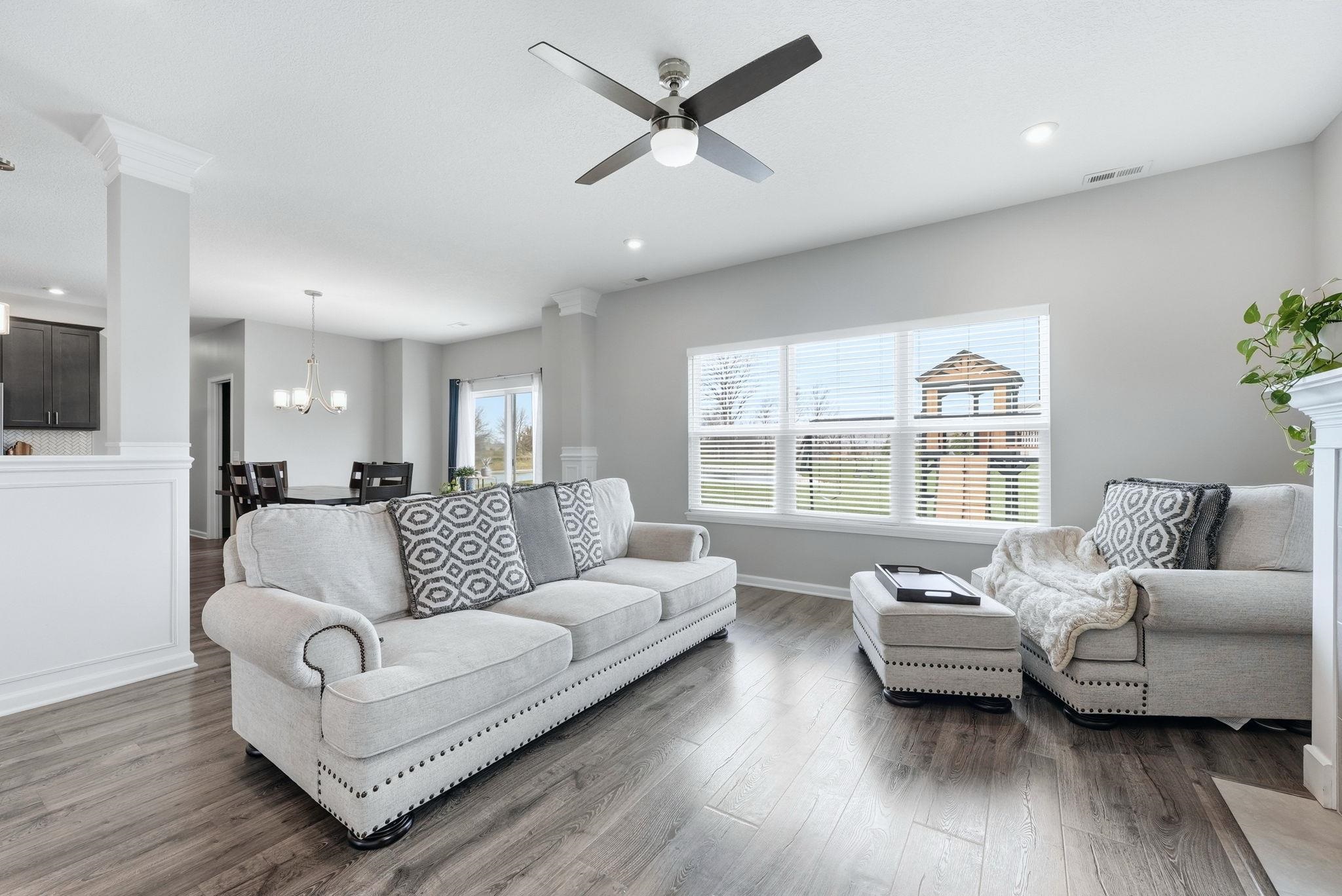 Living room featuring a ceiling fan, wood finished floors, and suspended lighting