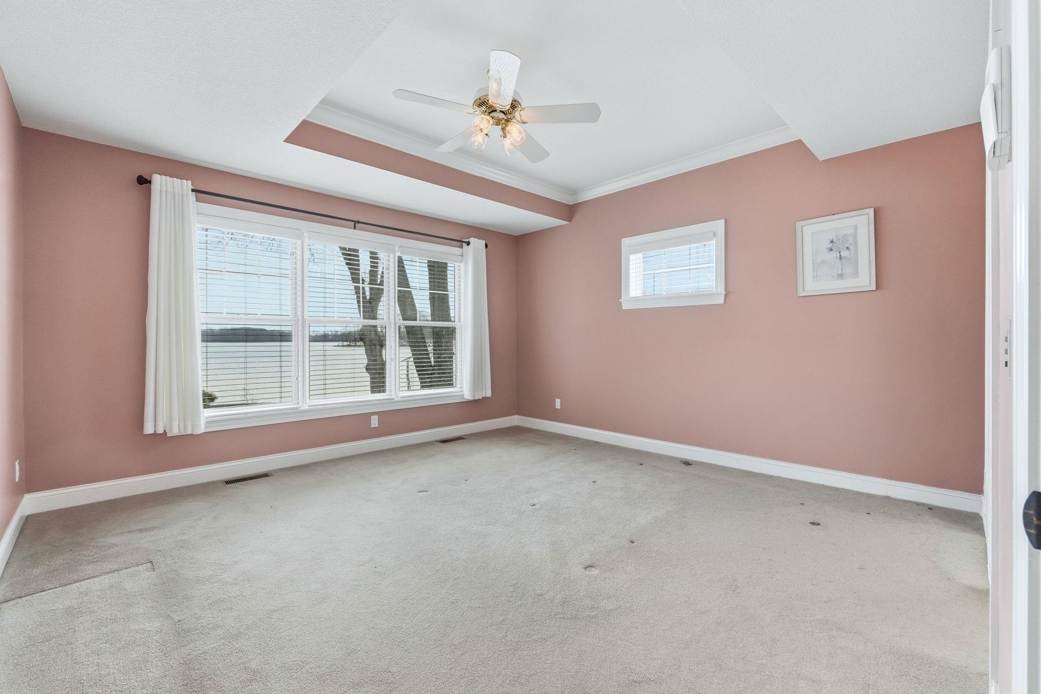 Spare room with a ceiling fan, light colored carpet, and crown molding