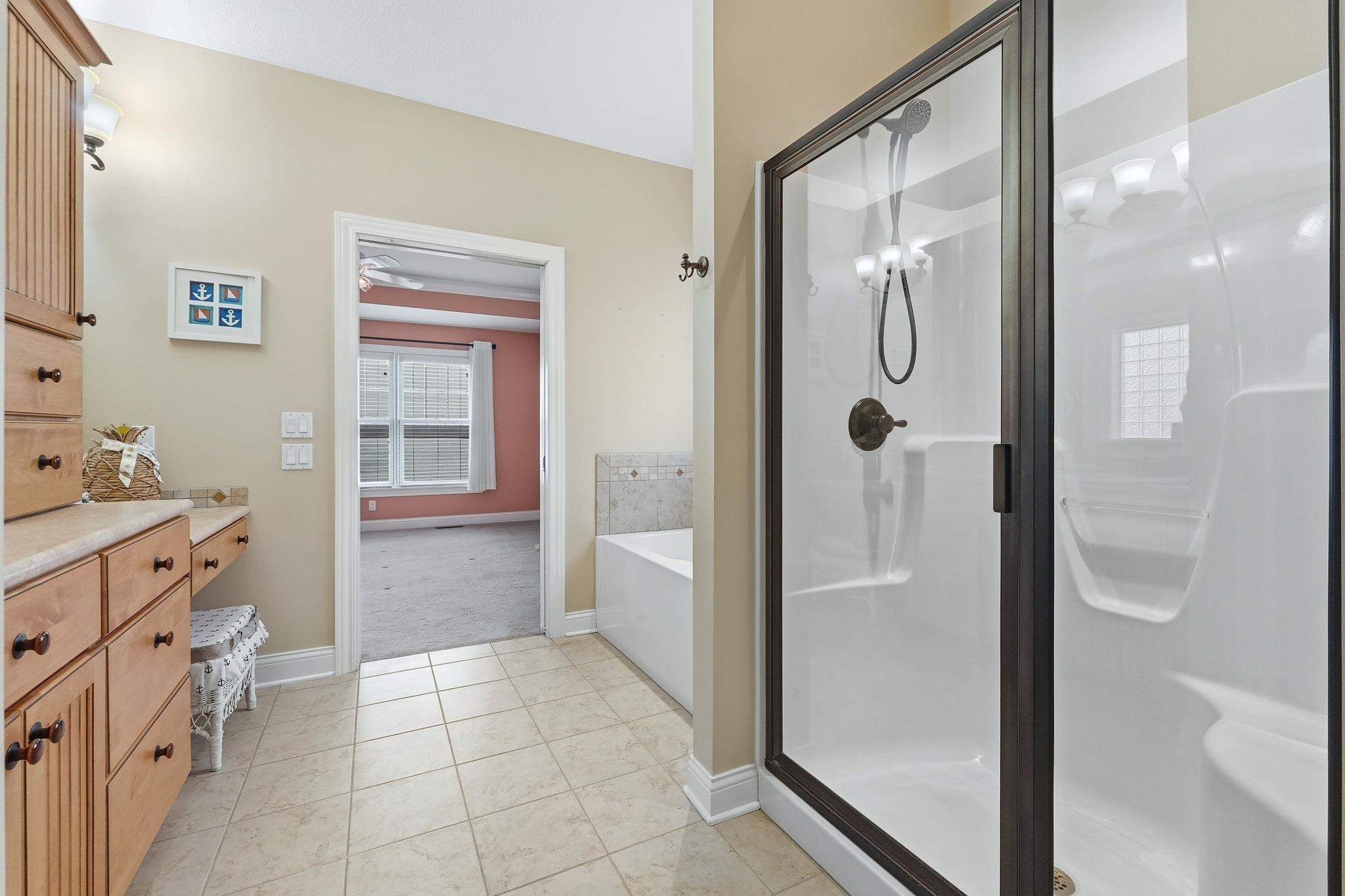 Full bath with a garden tub, a shower stall, vanity, and light colored carpet