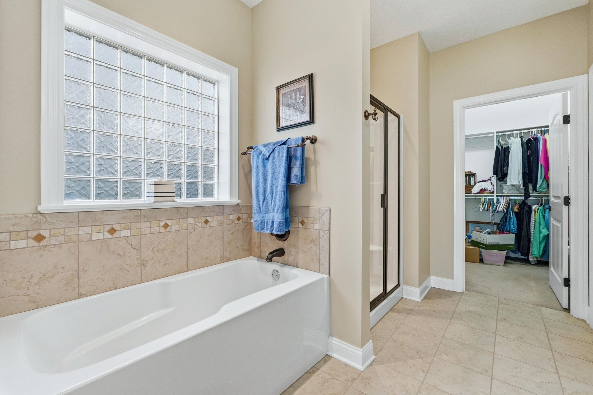 Bathroom with a shower stall, a garden tub, and a spacious closet