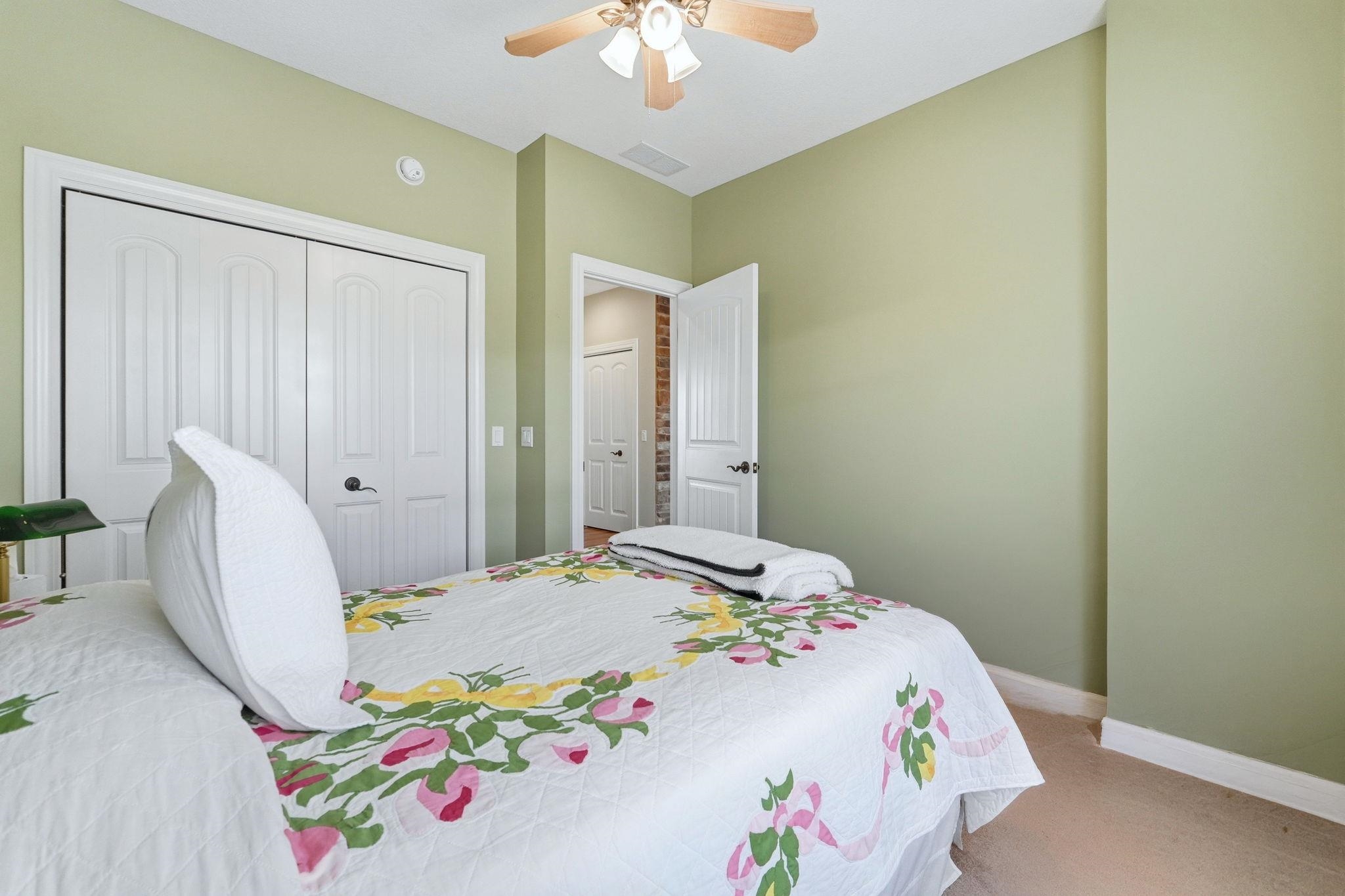 Bedroom with ceiling fan, a closet, and light carpet