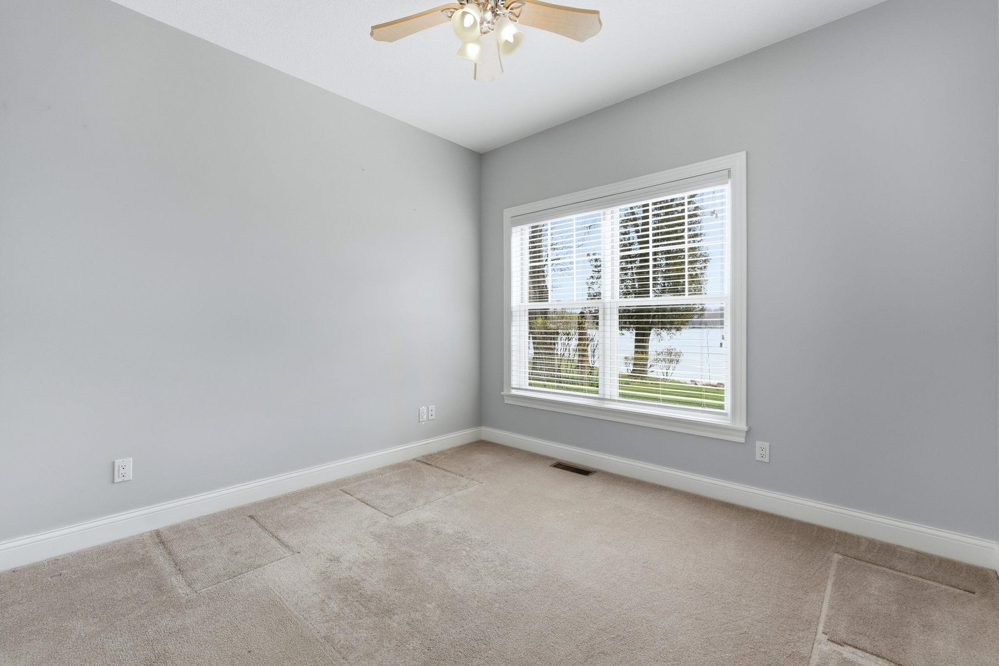 Unfurnished room with light colored carpet and a ceiling fan