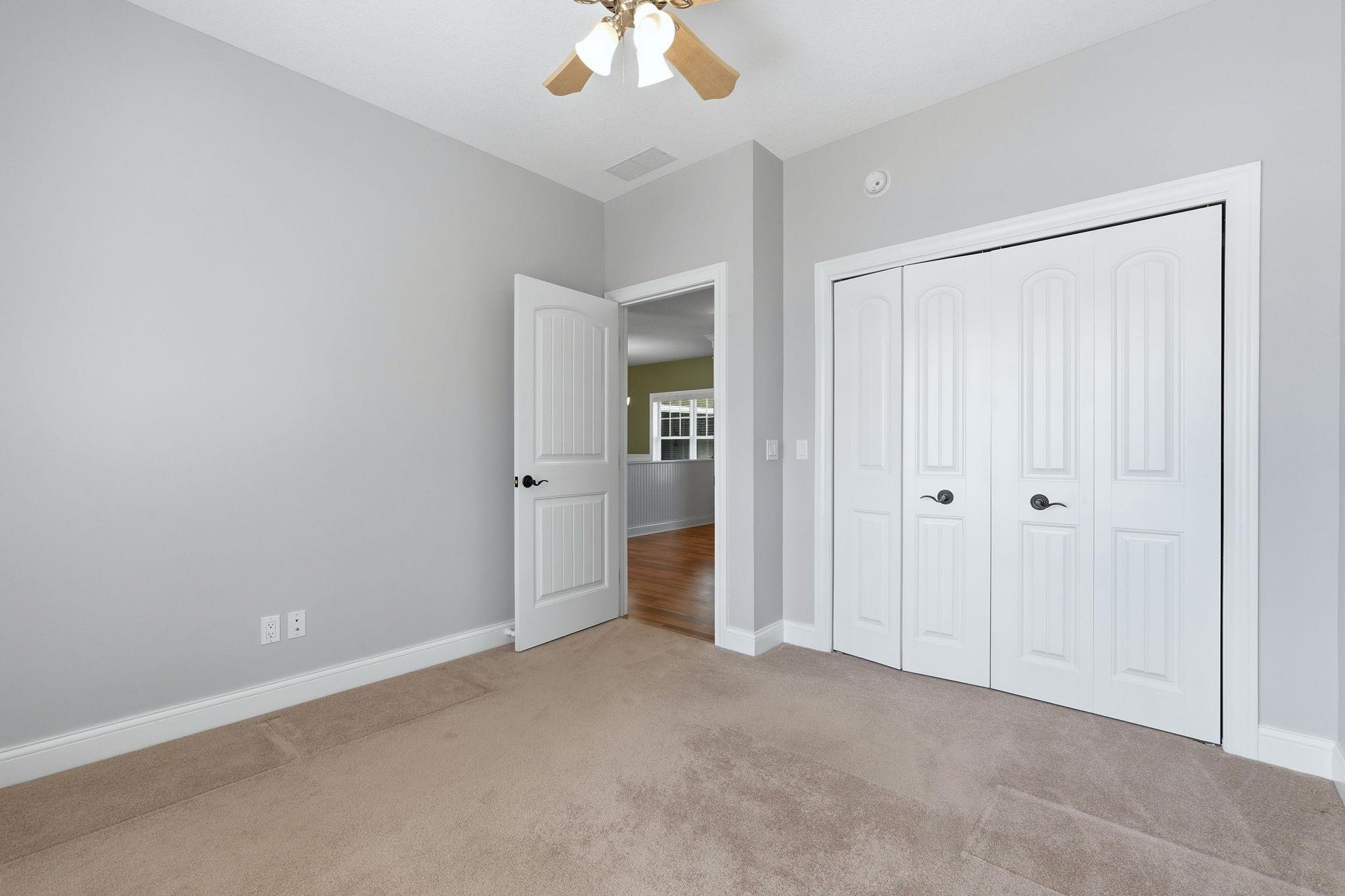 Unfurnished bedroom featuring light carpet, a closet, and a ceiling fan