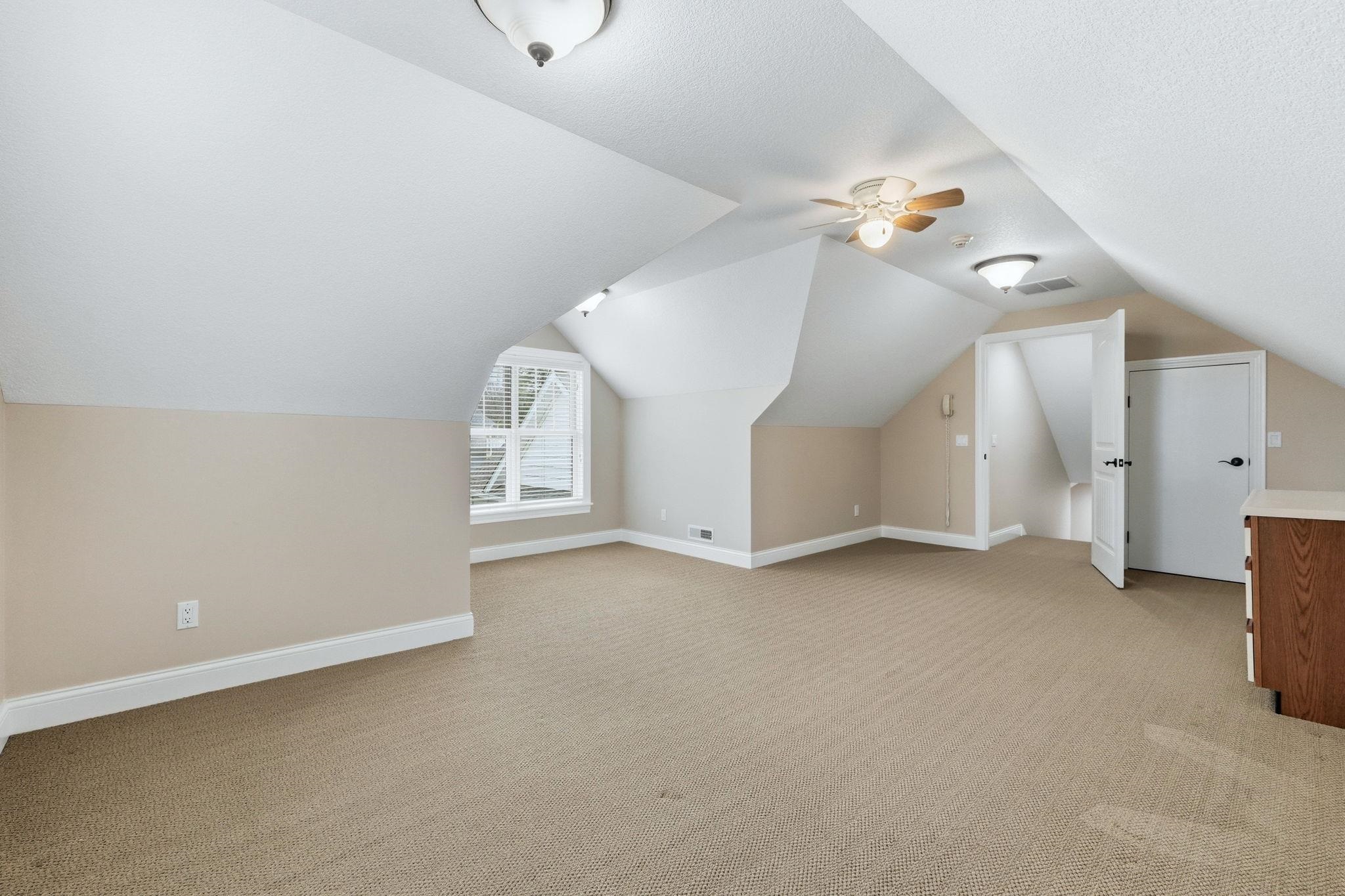Additional living space with light carpet, ceiling fan, and lofted ceiling