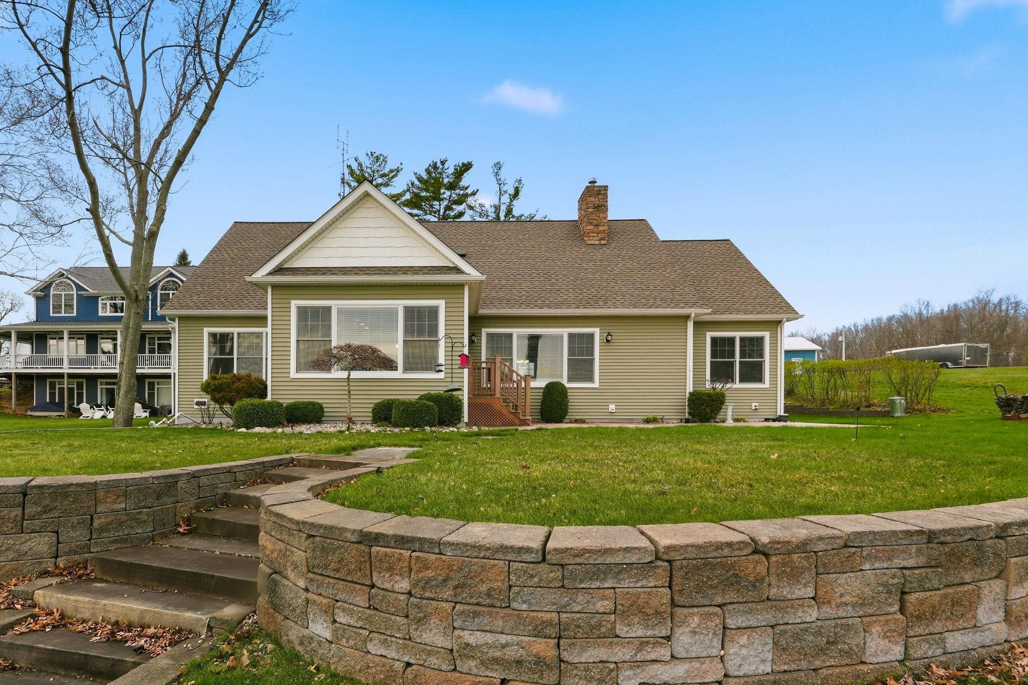 View of front facade with a front lawn, a chimney, and a shingled roof