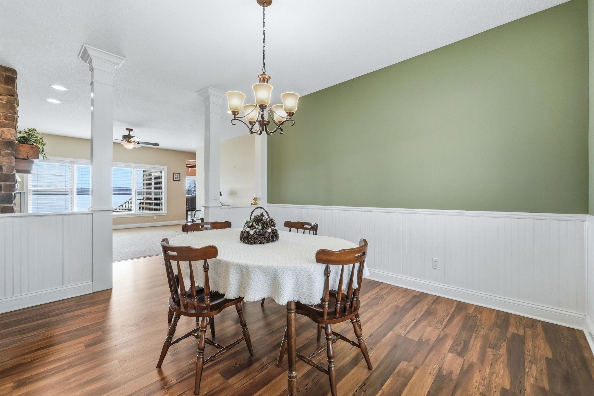 Dining area with wainscoting, a ceiling fan, dark wood-style flooring, and hanging lights
